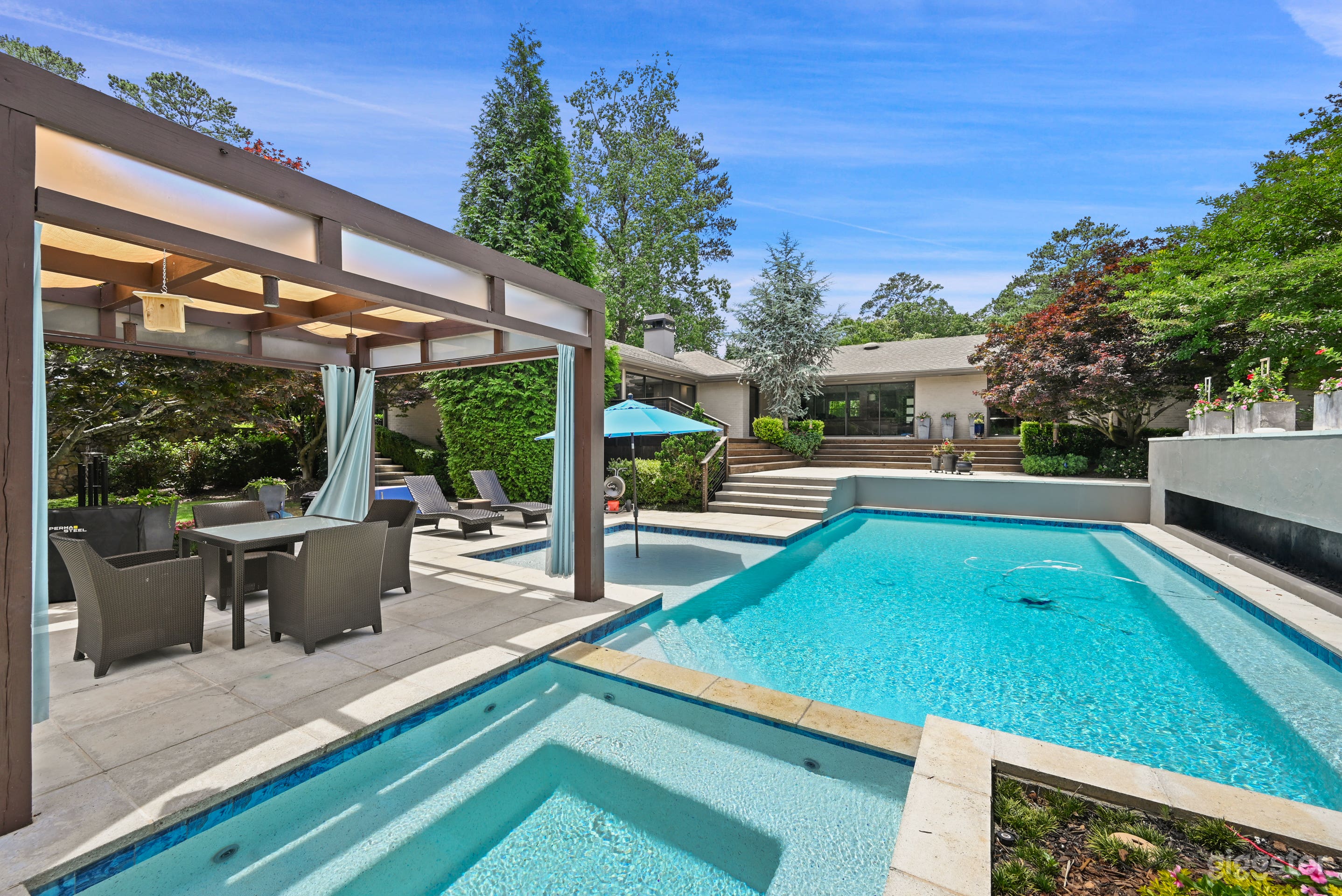 This backyard view is from the hot tub toward the house.  On the right is a fireplace that runs the complete length of the pool.