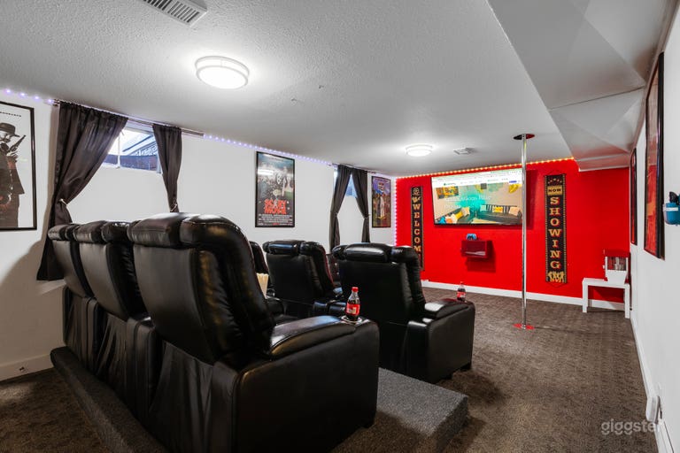  A theater room designed with bold red and black accents, featuring a pole dance area for added fun and a popcorn maker for the ultimate movie experience. 