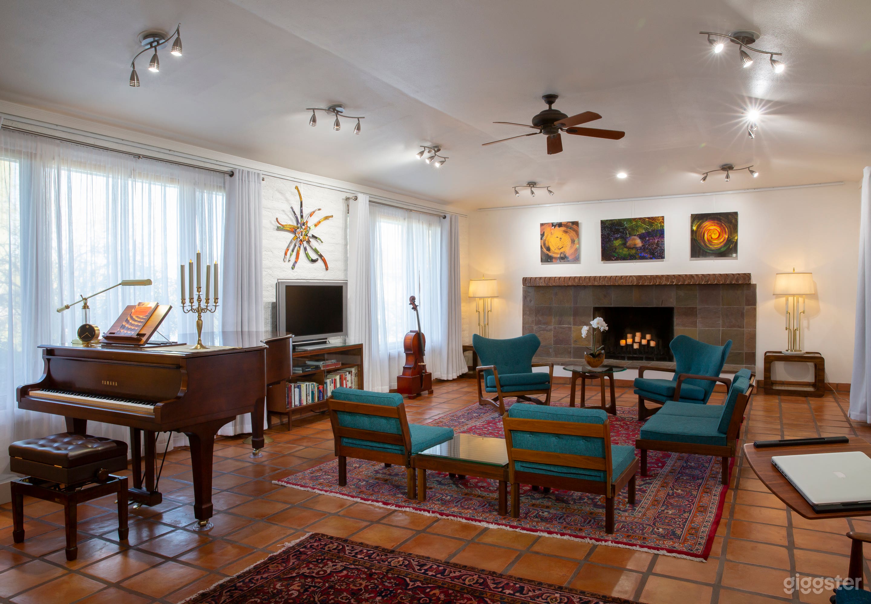 Bright, airy space with whitewashed brick walls featuring natural light, Mexican Saltillo tile, Adrian Pearsall chairs, Tommi Parzinger lamps, and a Yamaha C3 piano.
