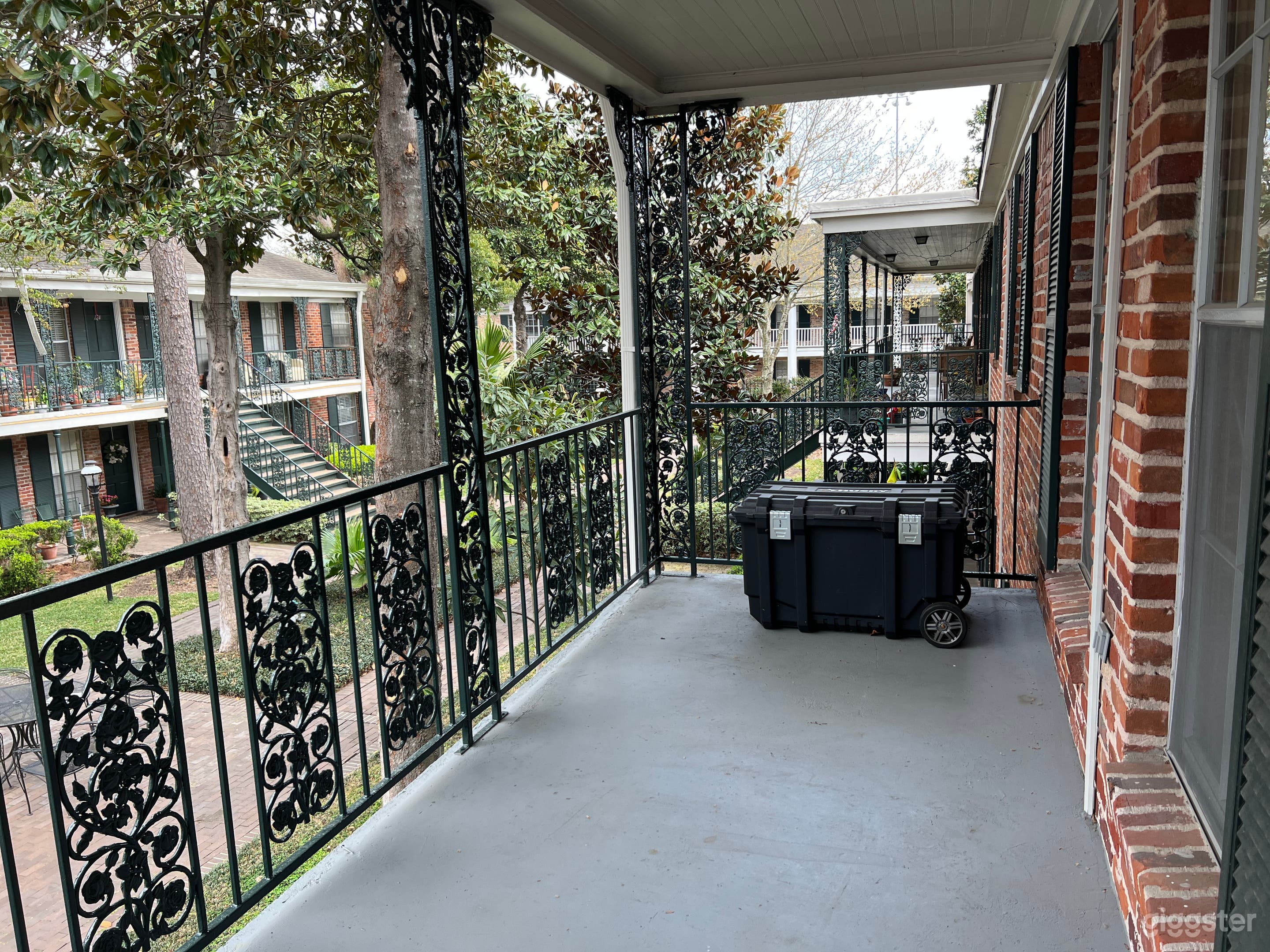 Roomy Creole iron and brick porch with beautiful greenery!