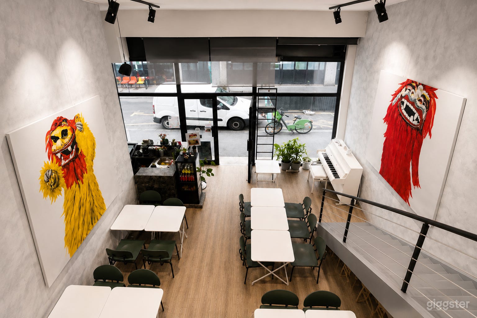 Vue de la mezzanine surplombant l'espace principal, avec de grandes fenêtres donnant sur la rue et une disposition flexible des sièges.