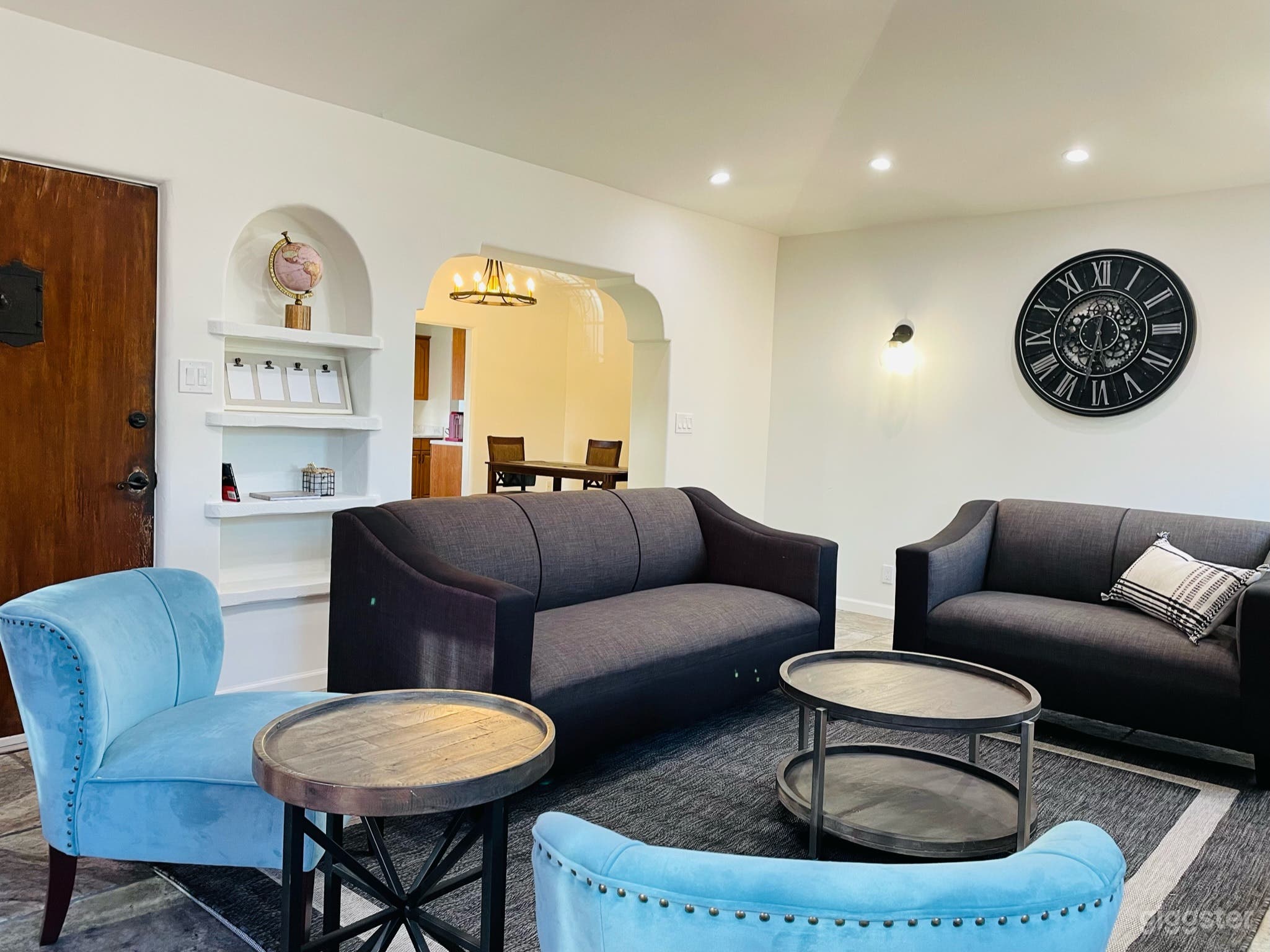 Spacious well-lit living room area with vaulted ceilings and plenty of natural and/or recessed lighting. Stone fireplace is purely decorative. 