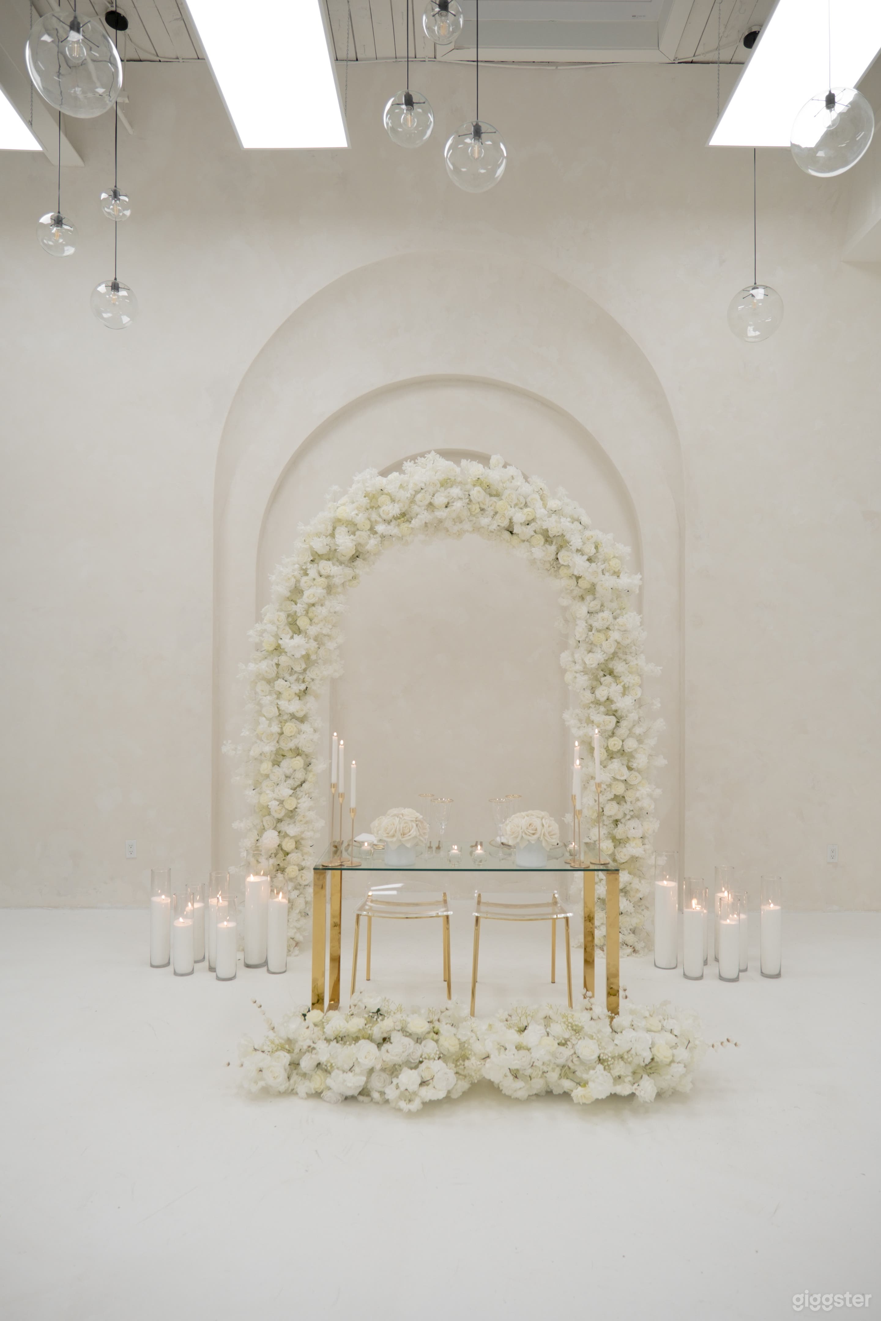 Stylish table setup beneath a beautiful white floral arch. Ideal for weddings, receptions, and special events