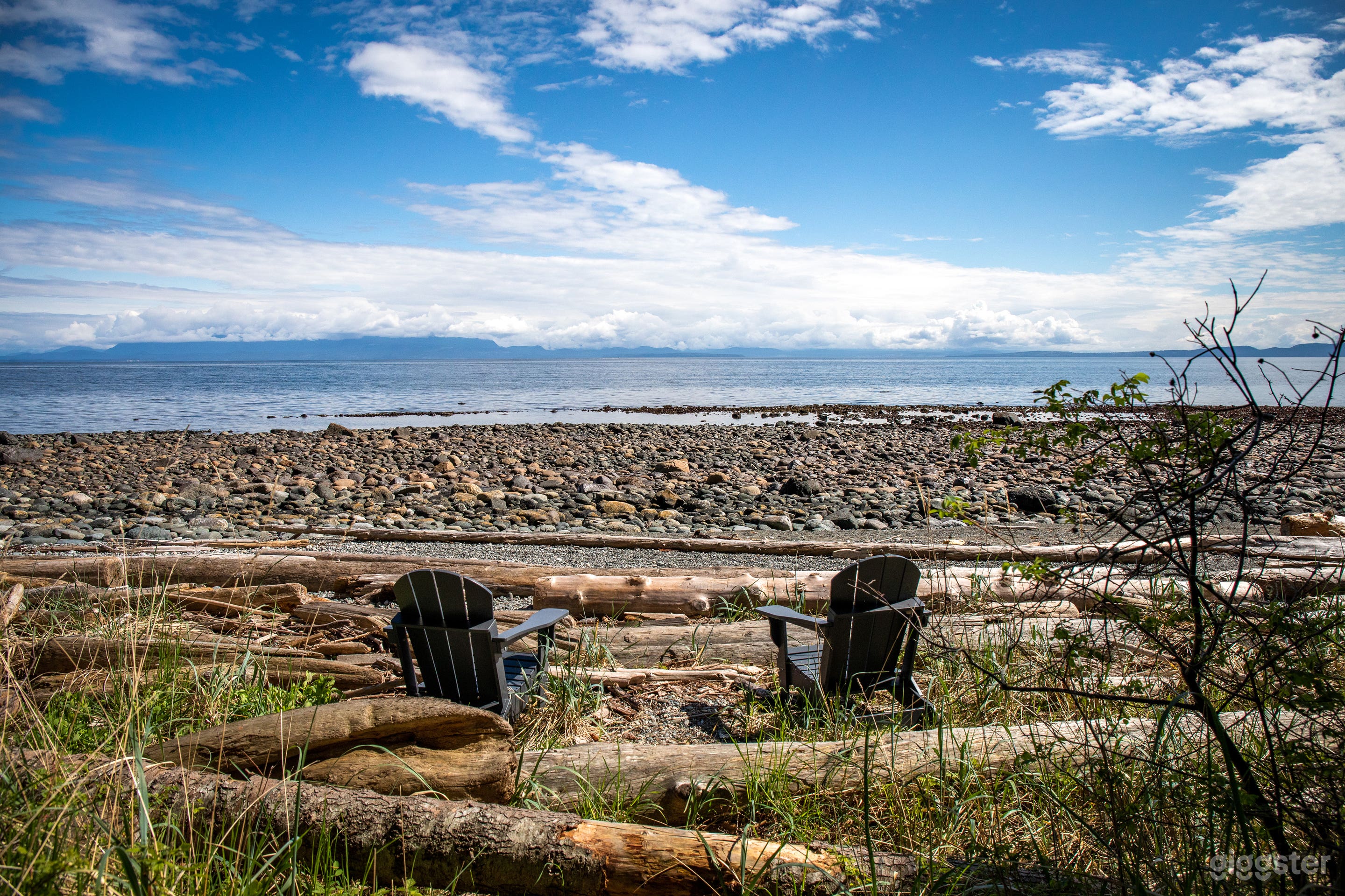 Rocky beach with driftwood logs and tidal pools, shown at low tide.  Beach fires are permissible when no fire ban.