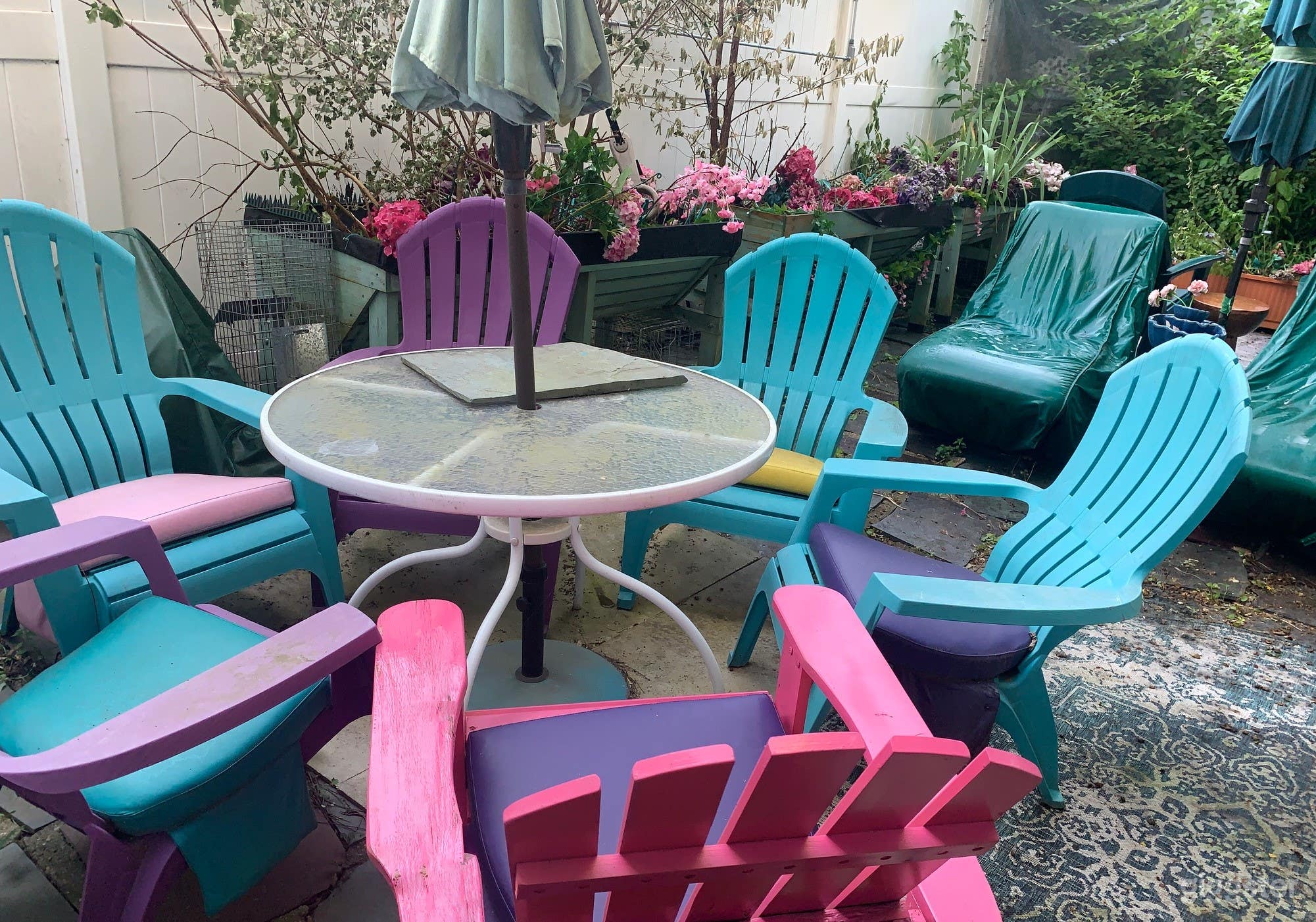 Colorful Intimate Seating Area With Beach Umbrella in Back Yard - Flowering Beds in Background