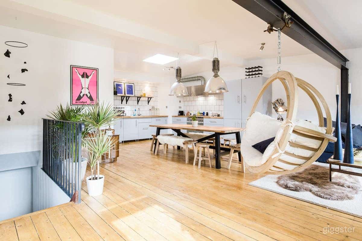 The main space contains a kitchen and living room combined with a white mini grand piano and movable swinging chair. 