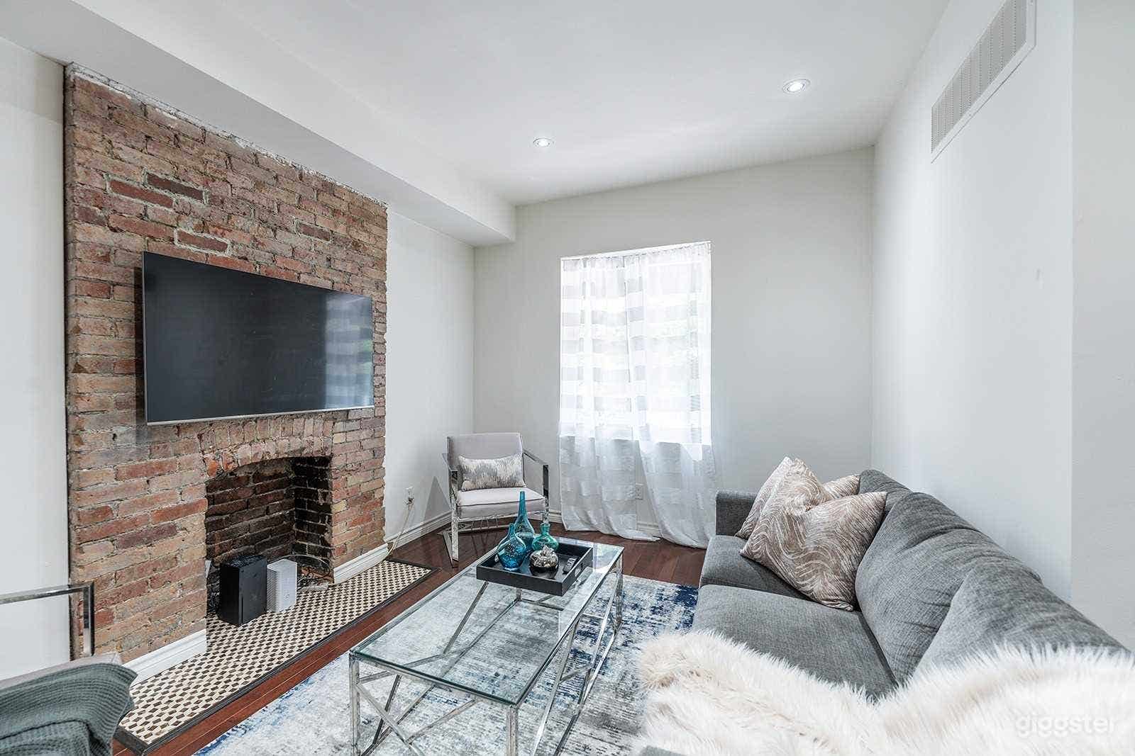 The living room has a large bright window and brick fireplace. 