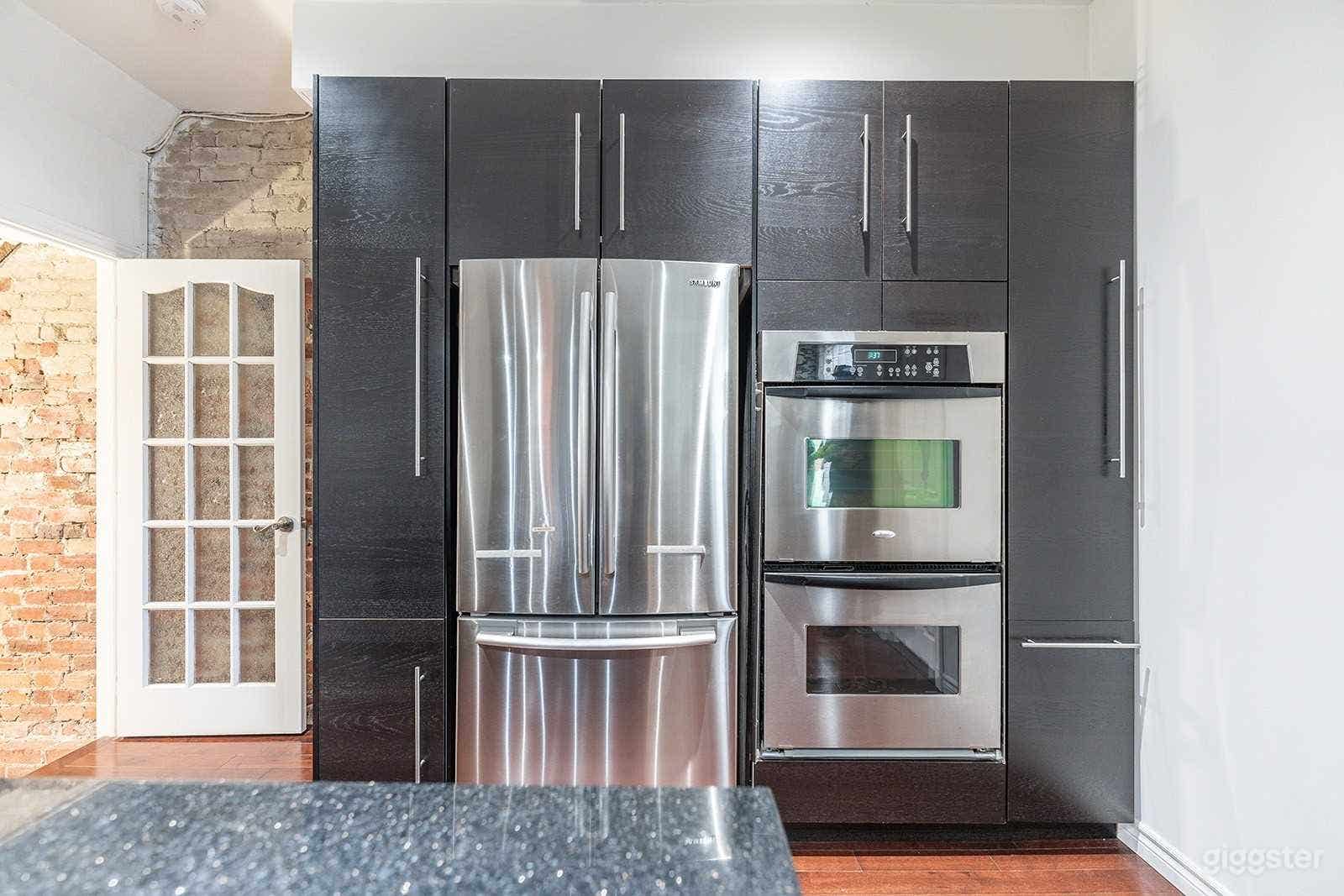 The kitchen features stainless steel appliances, gas stove, white brick backsplash, large kitchen island with its own sink (2 kitchen sinks in total), a modern wine/drink fridge, and window that faces the beautiful backyard. 
