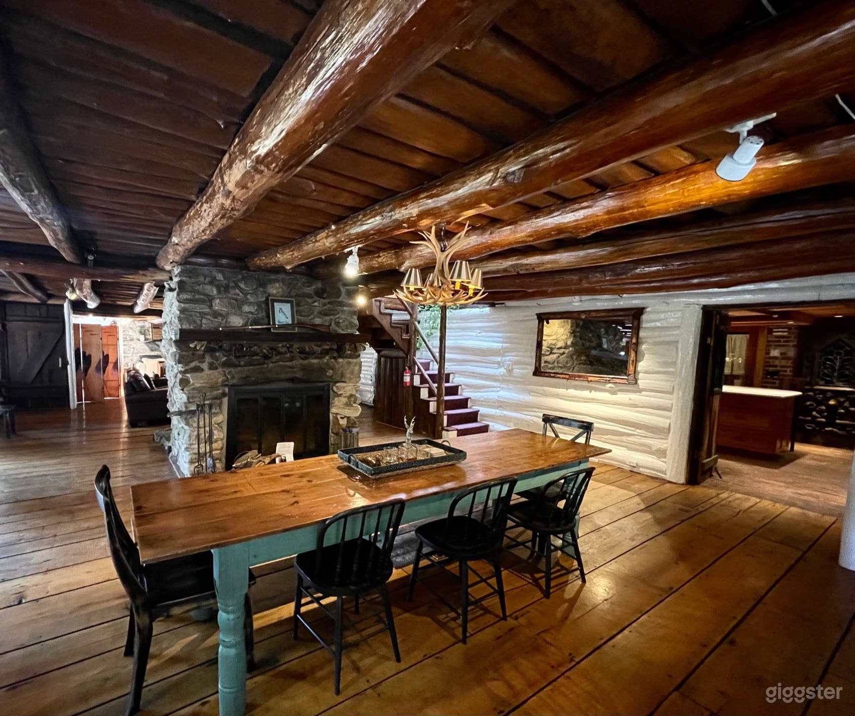 Open dining area highlighted by wood burning stone fireplace, exposed log cabin ceiling and stunning wide planked wood flooring. 