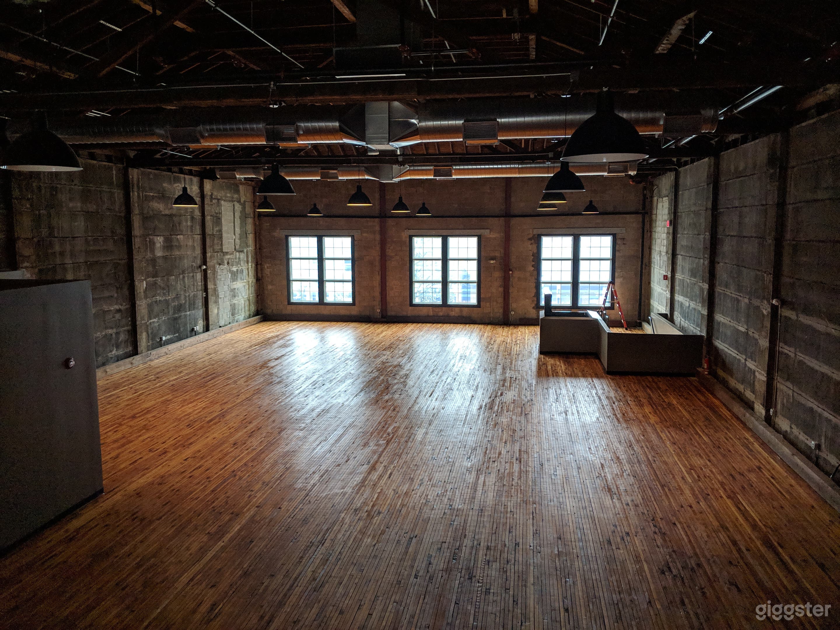 Blank slate empty space with warm wood floors, cathedral ceilings, and historic concrete walls