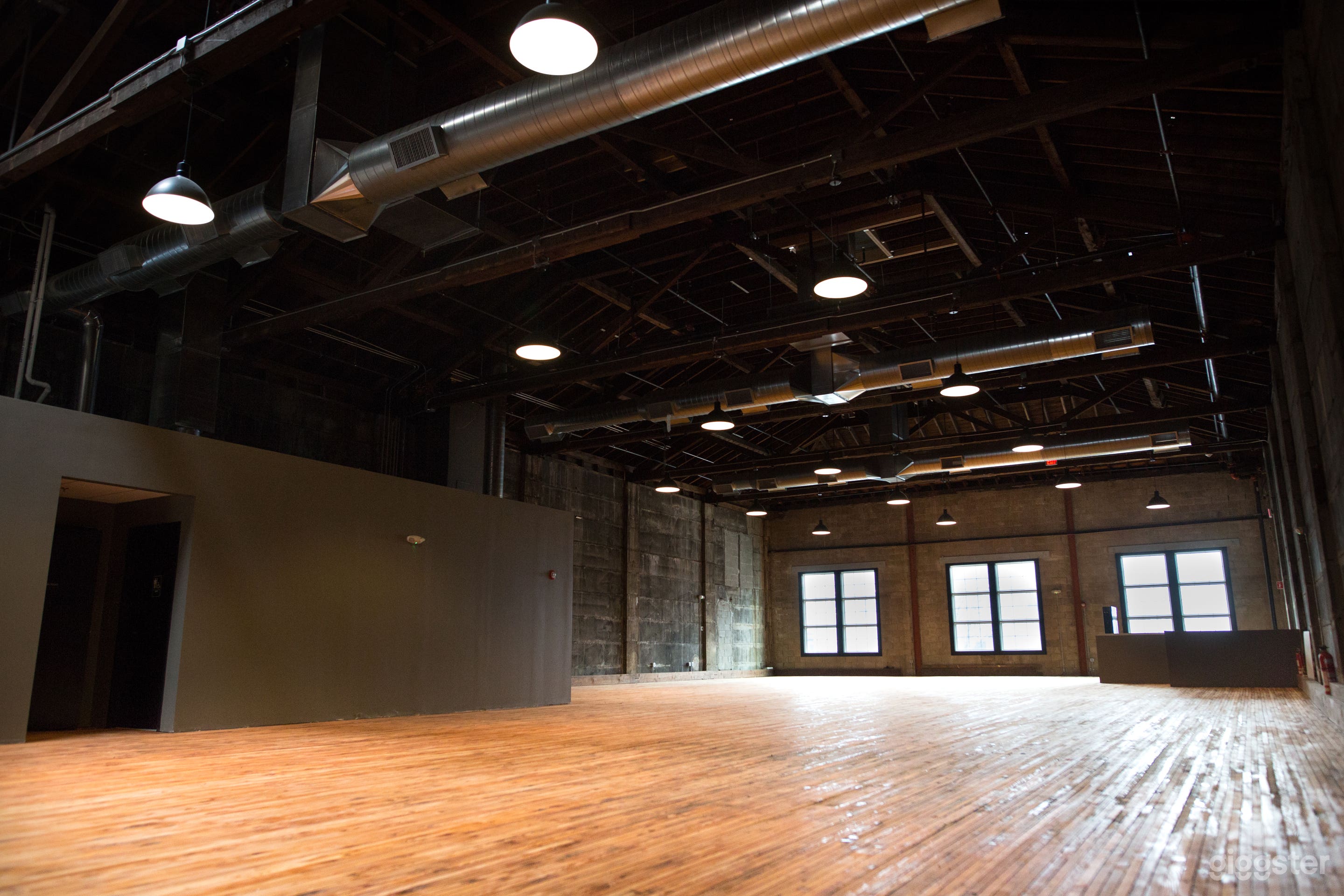 Blank slate empty space with warm wood floors, cathedral ceilings, and historic concrete walls