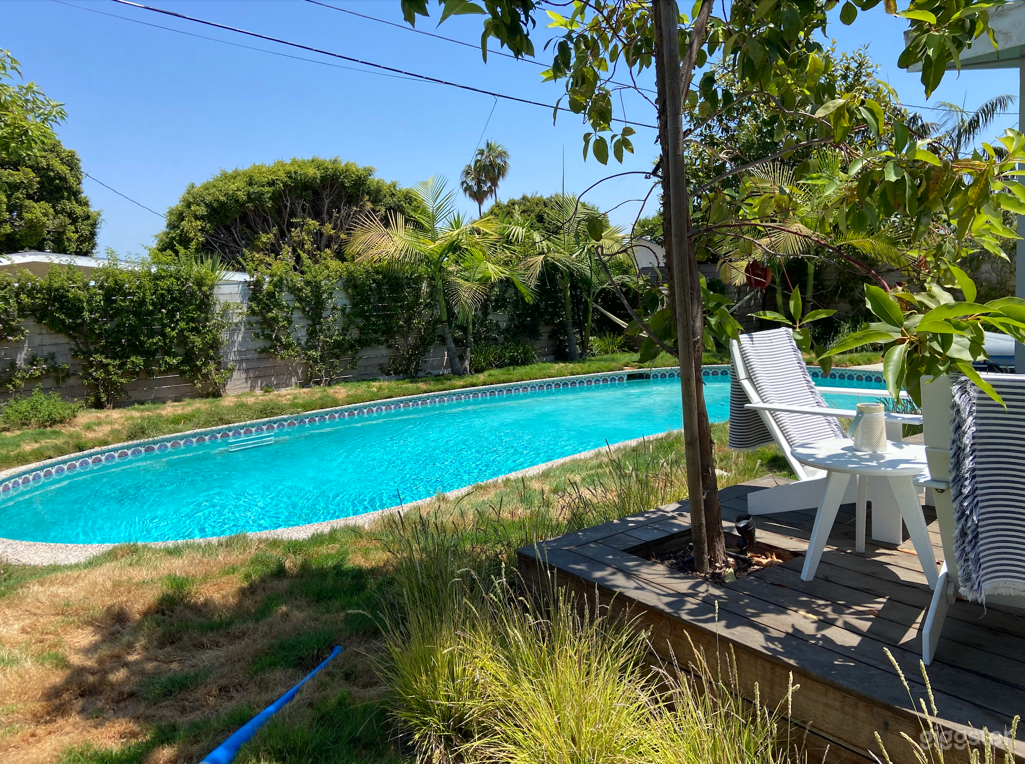 Backyard with pool, deck chairs, table, and lots of green space