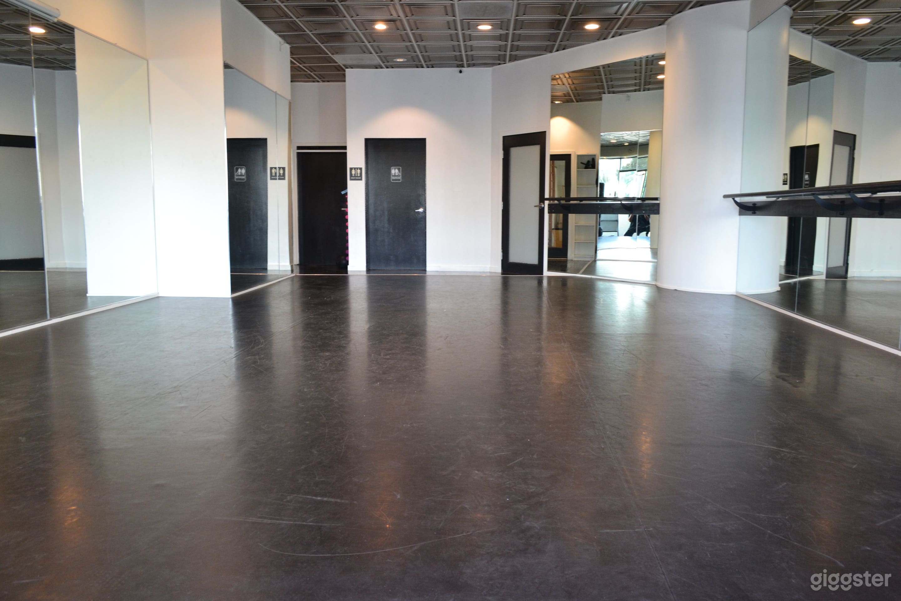 Dance studio with view of private bath door, office door, and back door. 