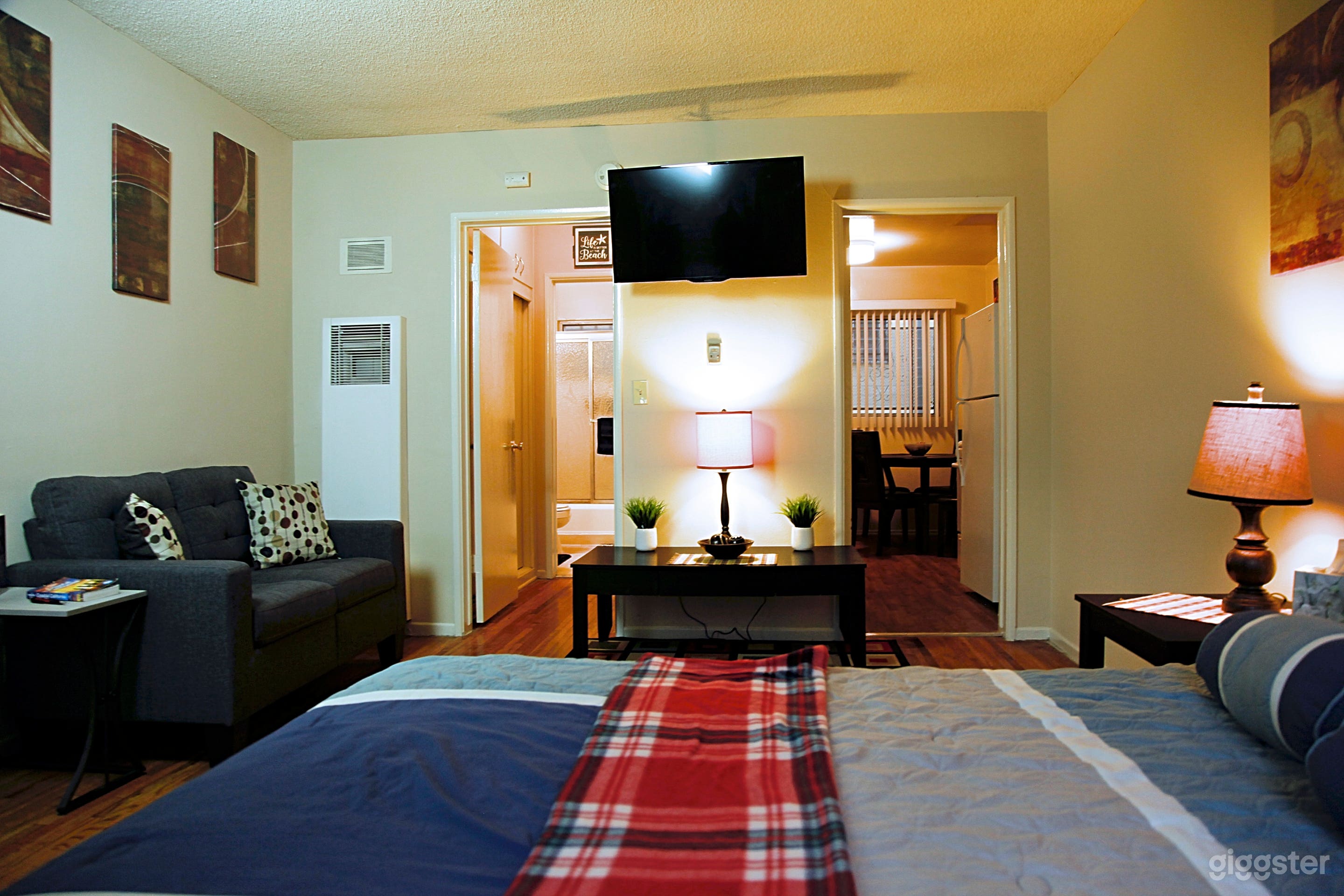 Studio Bedroom with love seat couch, small desk across from bed and 41in wall mounted TV.