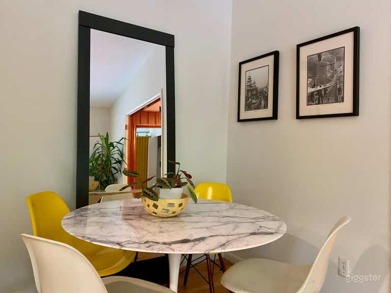  The breakfast nook, off the kitchen, features a buttery leather couch and this marble dining table with seating for 4. Playful Eames chairs pick up and continue a fun theme of yellow highlights throughout the house.  
