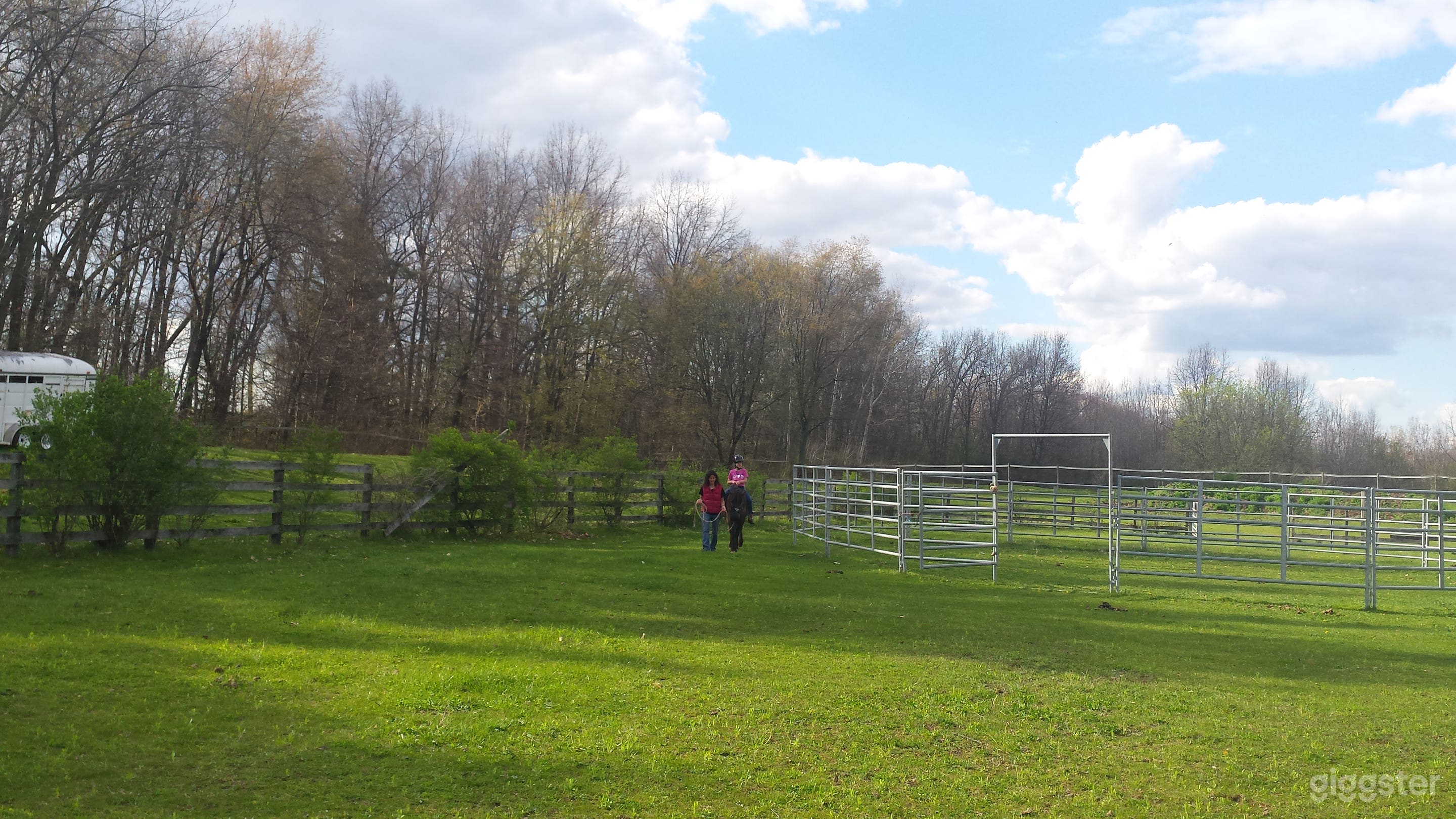 Outdoor arena 100'x200' with 50' diameter rodeo grade 6' high round pen. Grass footing, riding area/spectator seating on hilly area to left