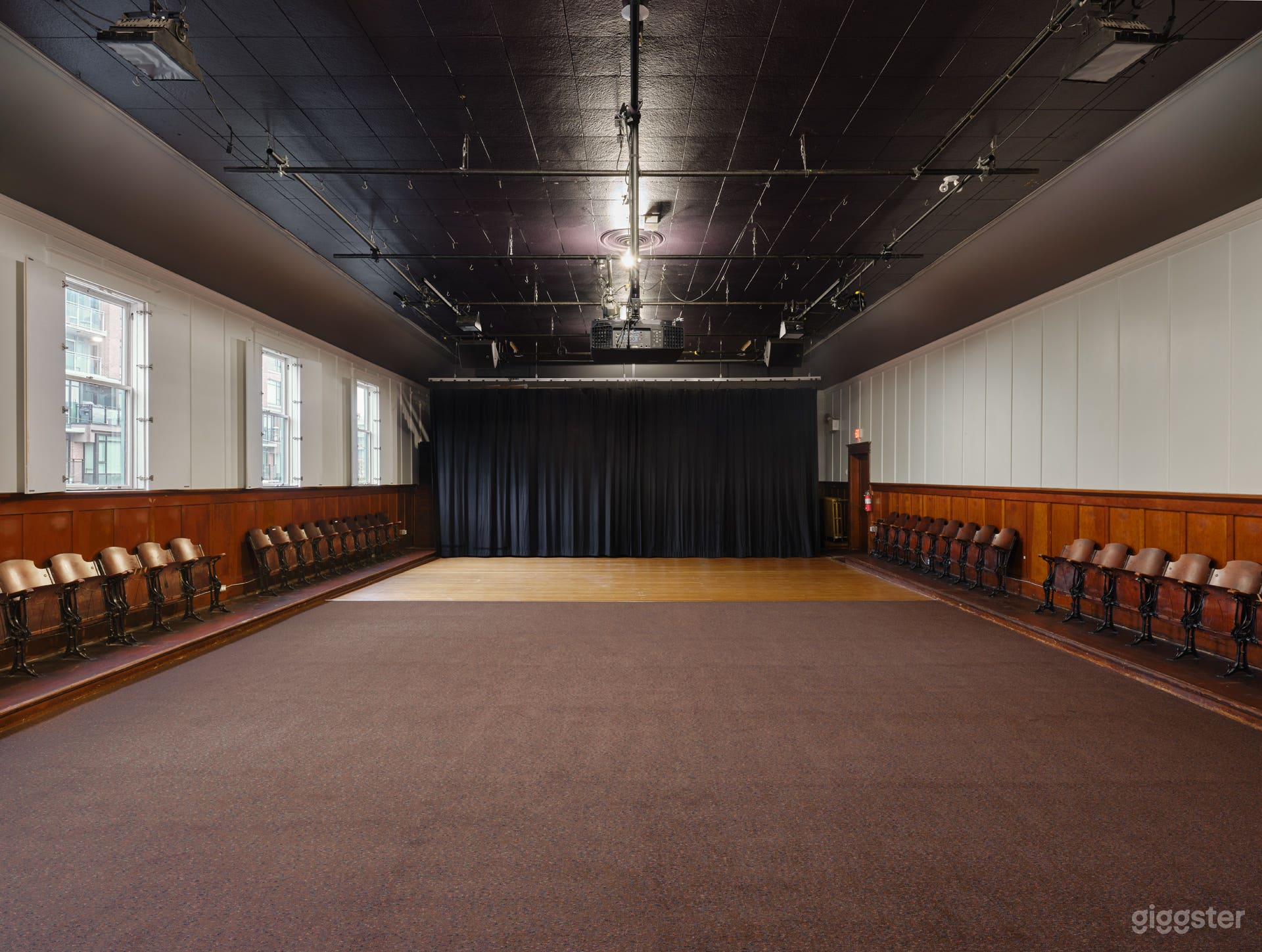 Interior of the hall featuring the hardwood stage, natural light streaming through open windows, and the hall’s warm, vintage character on full display.