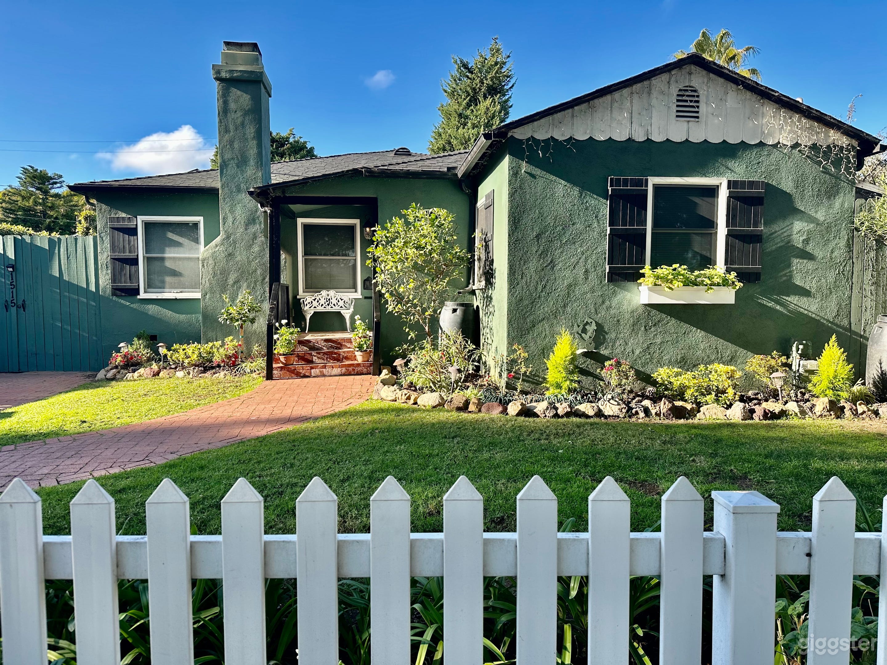Exterior landscaping includes white picket fence with aged-brick pathway and driveway. Original white scalloped roofline trim and window box with flowers add to the cottage feel!