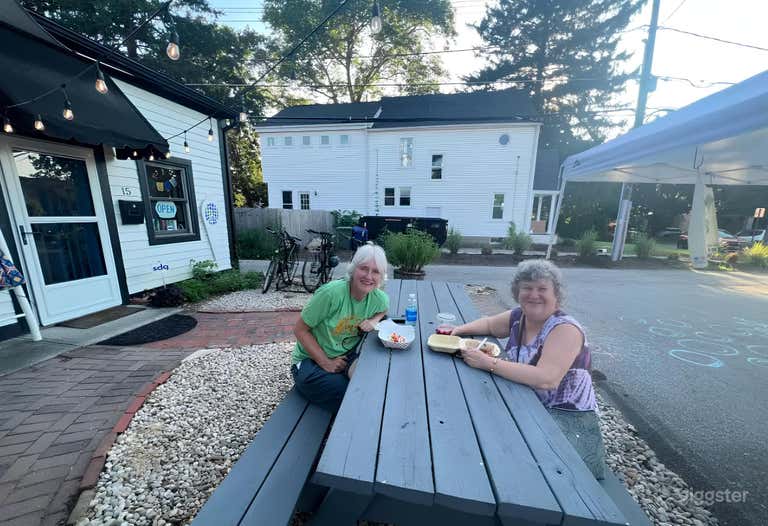  Front of space with picnic tables. There is another table to the right of this image. The house in the background is rentable thru Airbnb as well. 