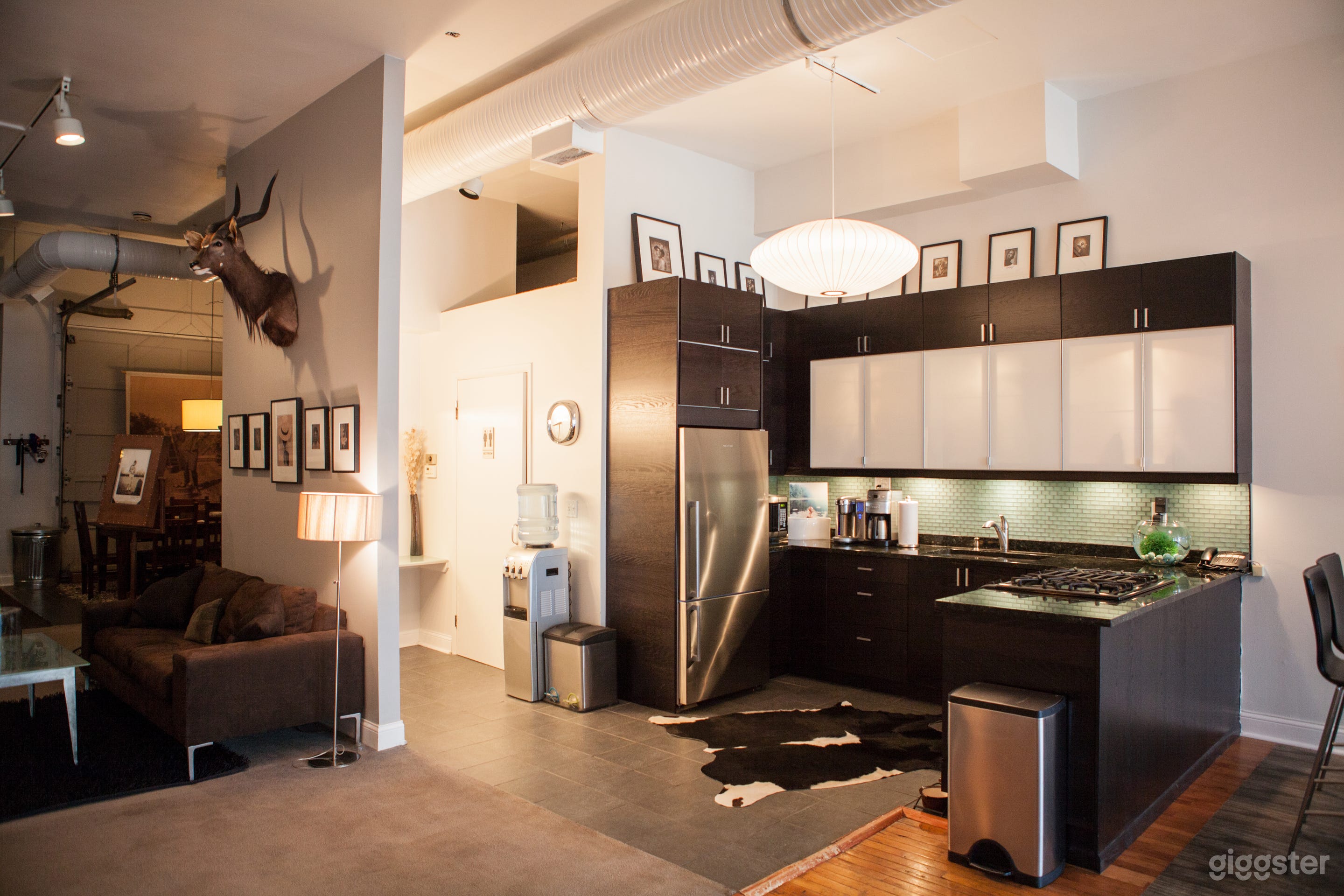 The studio opens up to a full kitchen complete with a stove top, sink, fridge, microwave, Keurig and plates/ mugs &amp; utensils. Tucked around the corner is a water cooler and the studio restroom.