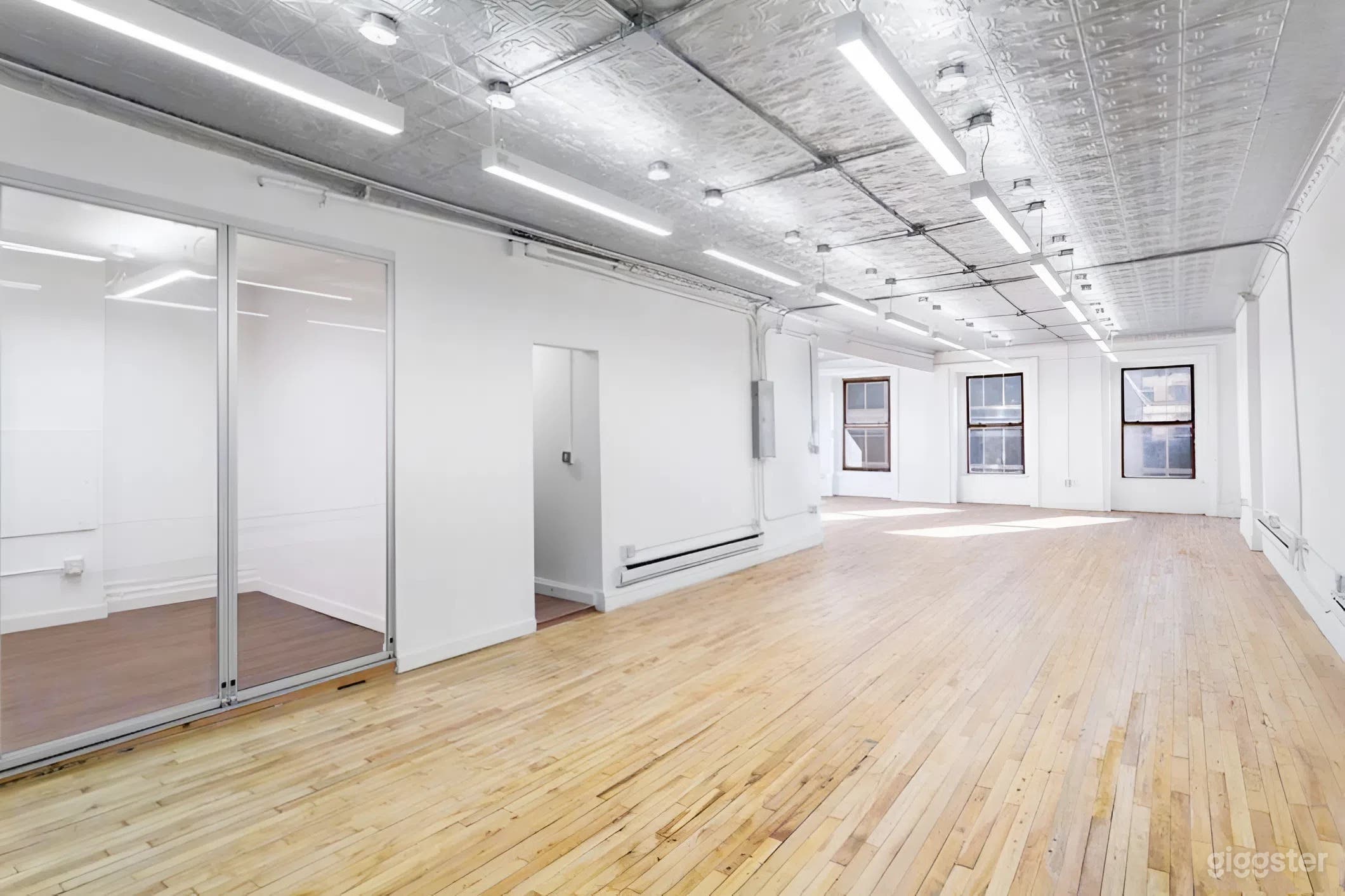 Expansive open-floor studio with natural light, polished hardwood floors, and industrial loft ceilings — ideal for film production, events, castings, and creative builds.