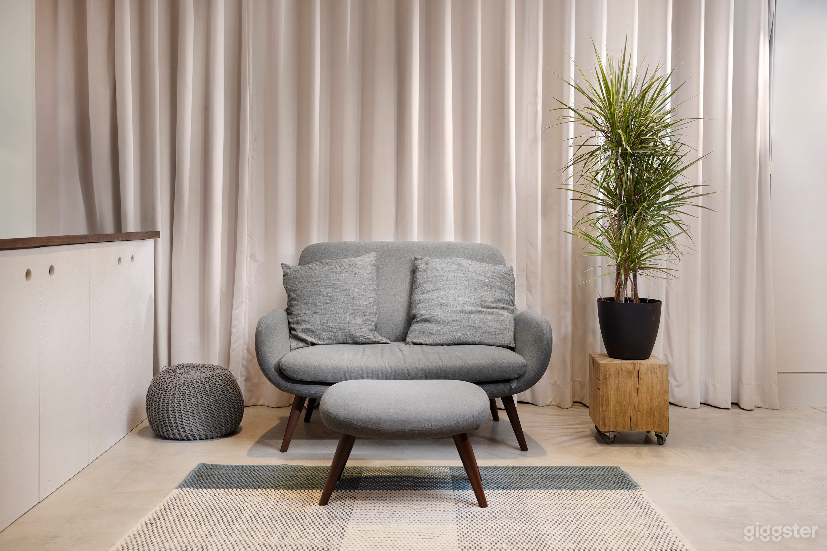 Back wall of open plan kitchen with curtain drawn. Concrete floor, large glass pivot door and skylights.