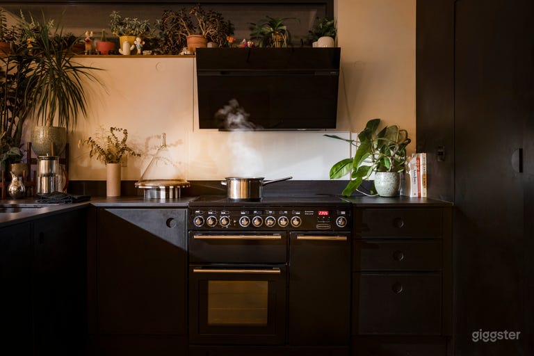  Open plan kitchen with concrete floor and black kitchen cupboards, countertops and pantry. Convection oven. 