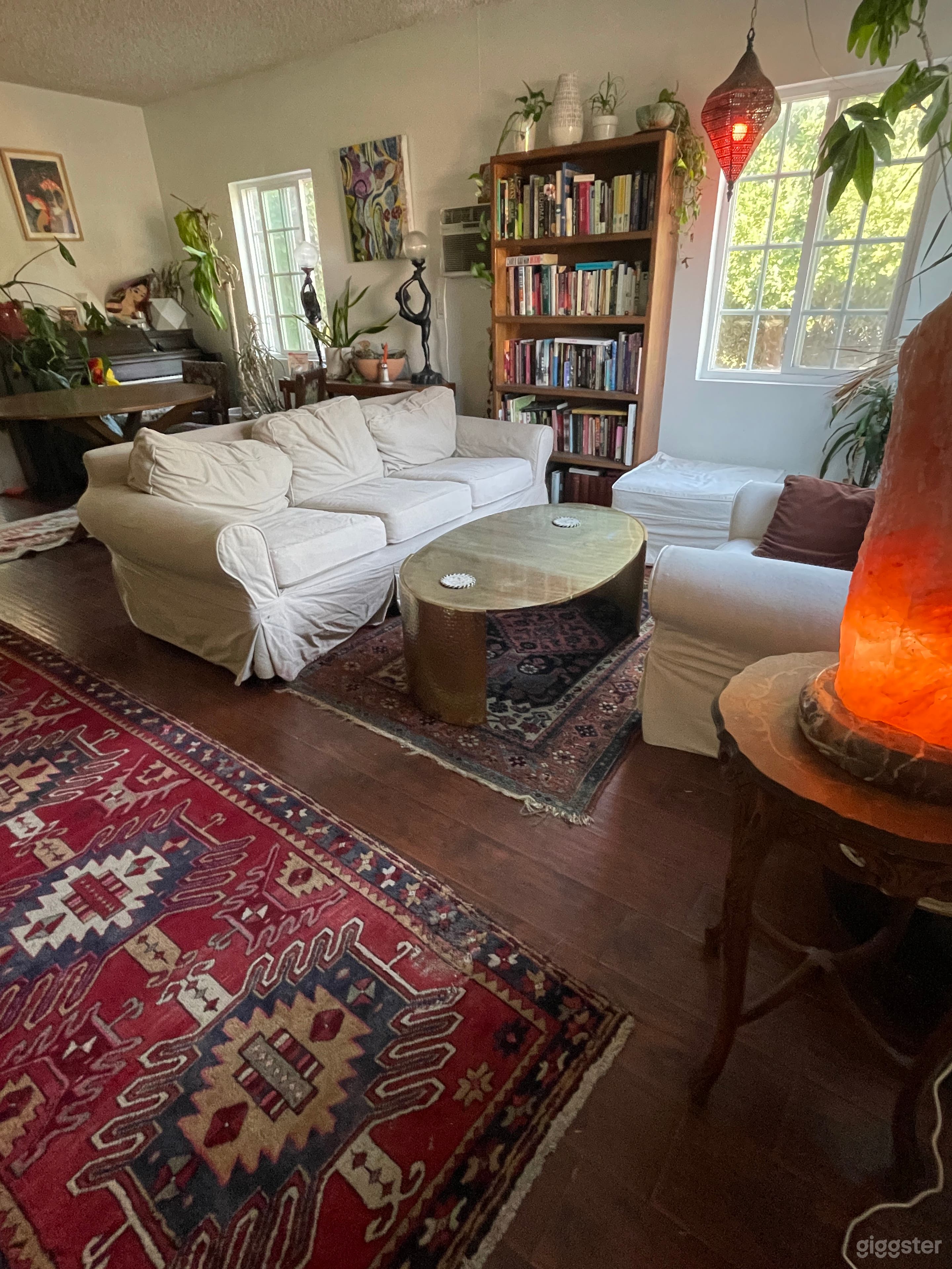 Cozy seating area facing windows. Enormous himalayan salt lamp and hammered copper coffee table. Bookshelf, piano and antique carpets.