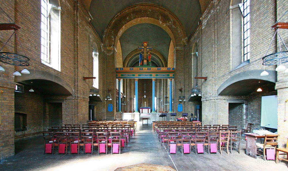The nave. Classic wooden chairs, bare concrete walls, good external light from tall windows.