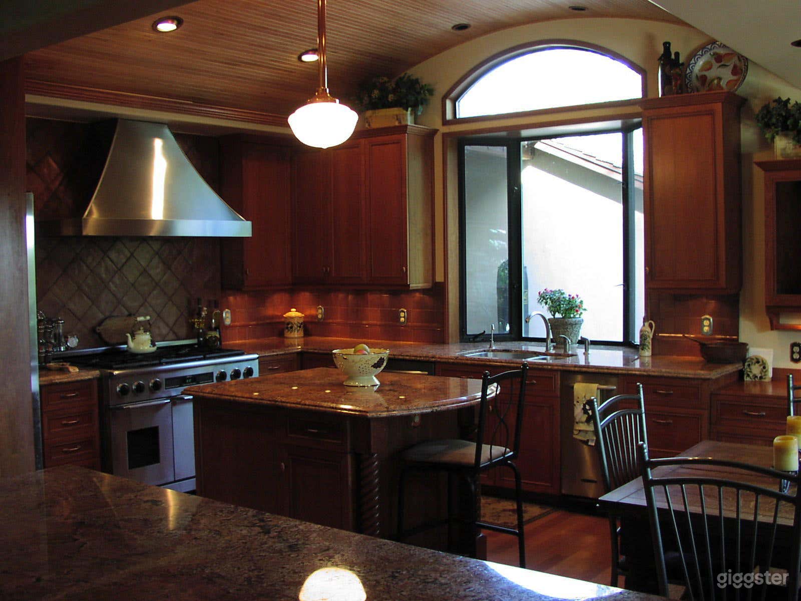 Kitchen with arched wood ceiling, stainless appliances, cherry cabinets, copper tile and granite counters