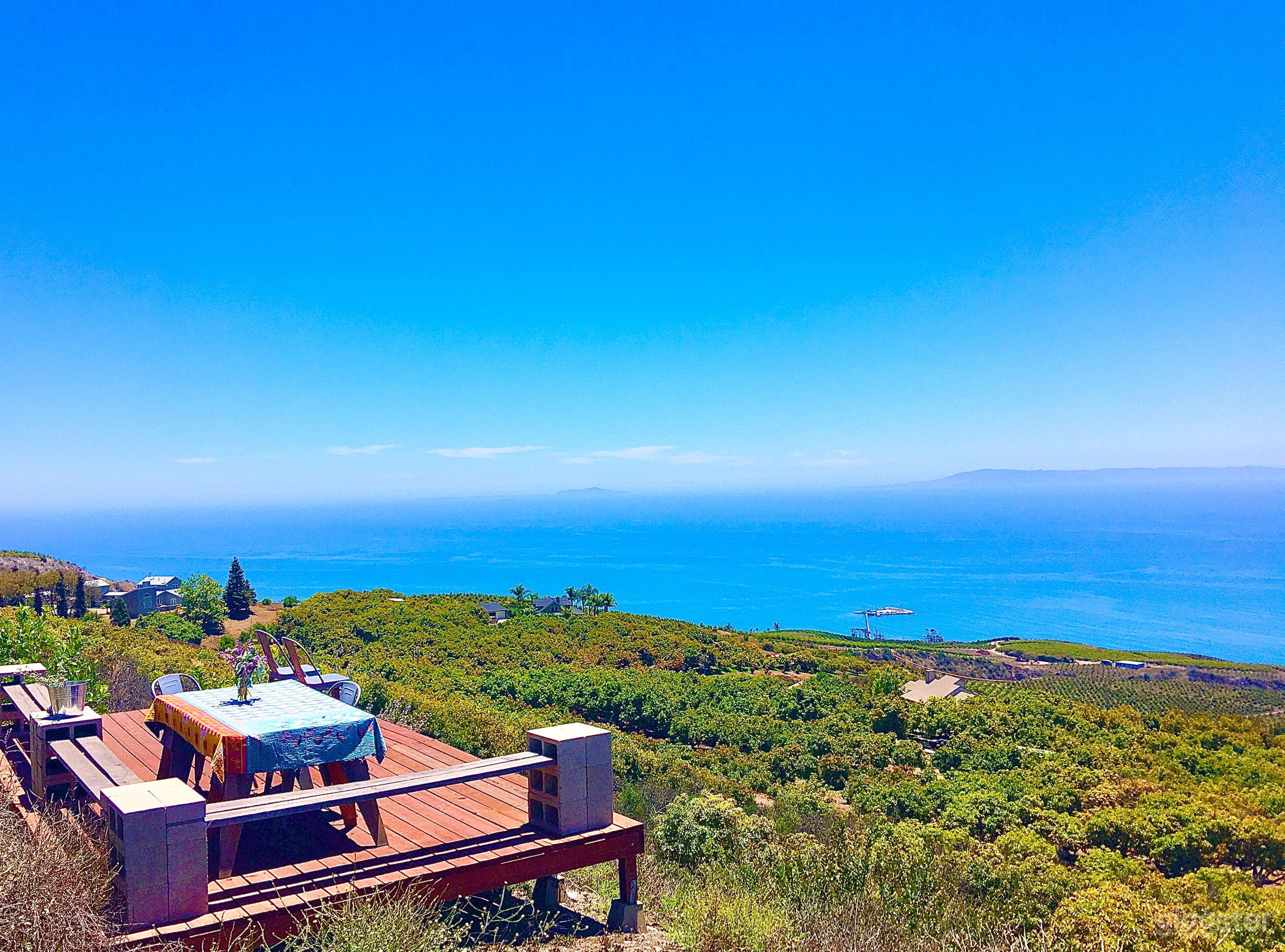 Table seating and benches on upper deck with panoramic view of the ocean and distant islands
