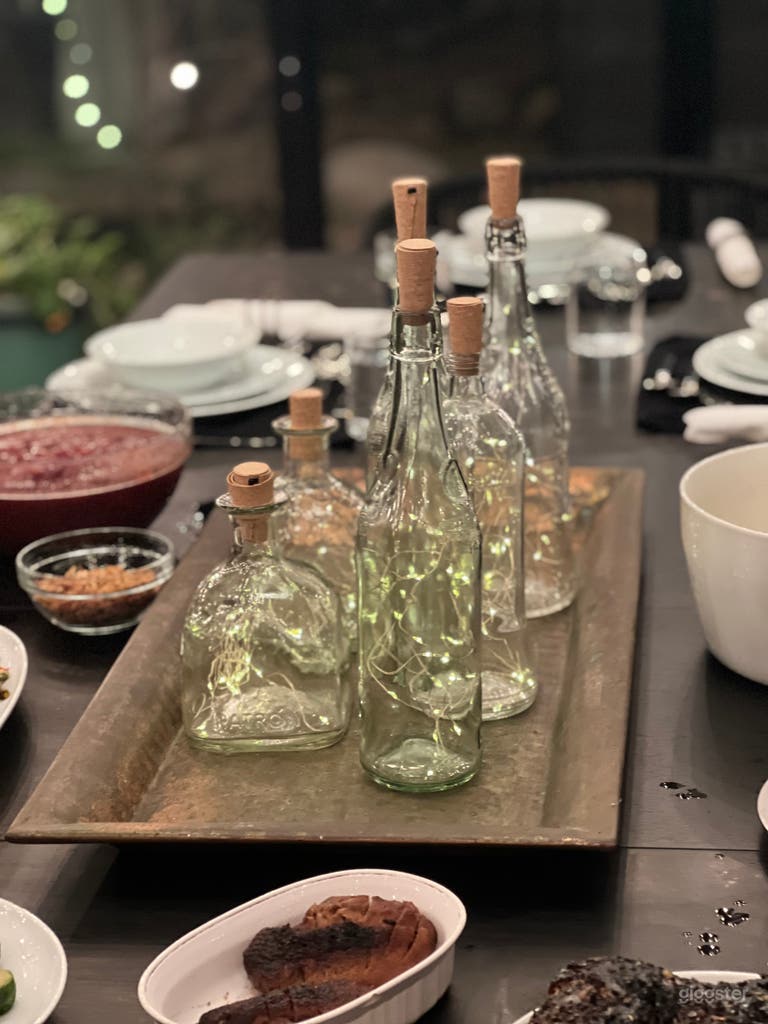  Various clear wine and liquor bottles with twinkle lights on copper patina tray. 