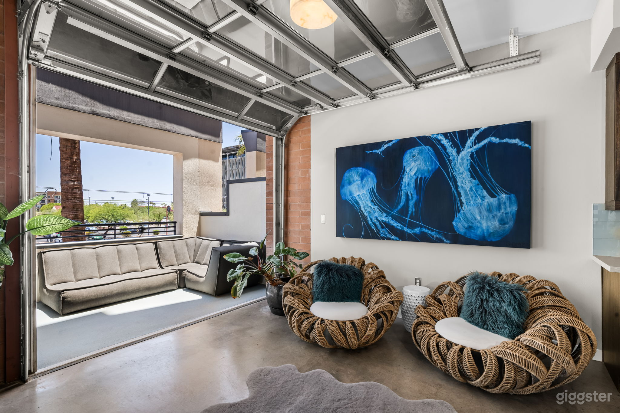 A common area adjacent to the kitchen.  It features two oversized custom chairs and beautiful artwork.  This space leads to the outdoor patio using the all glass garage door.