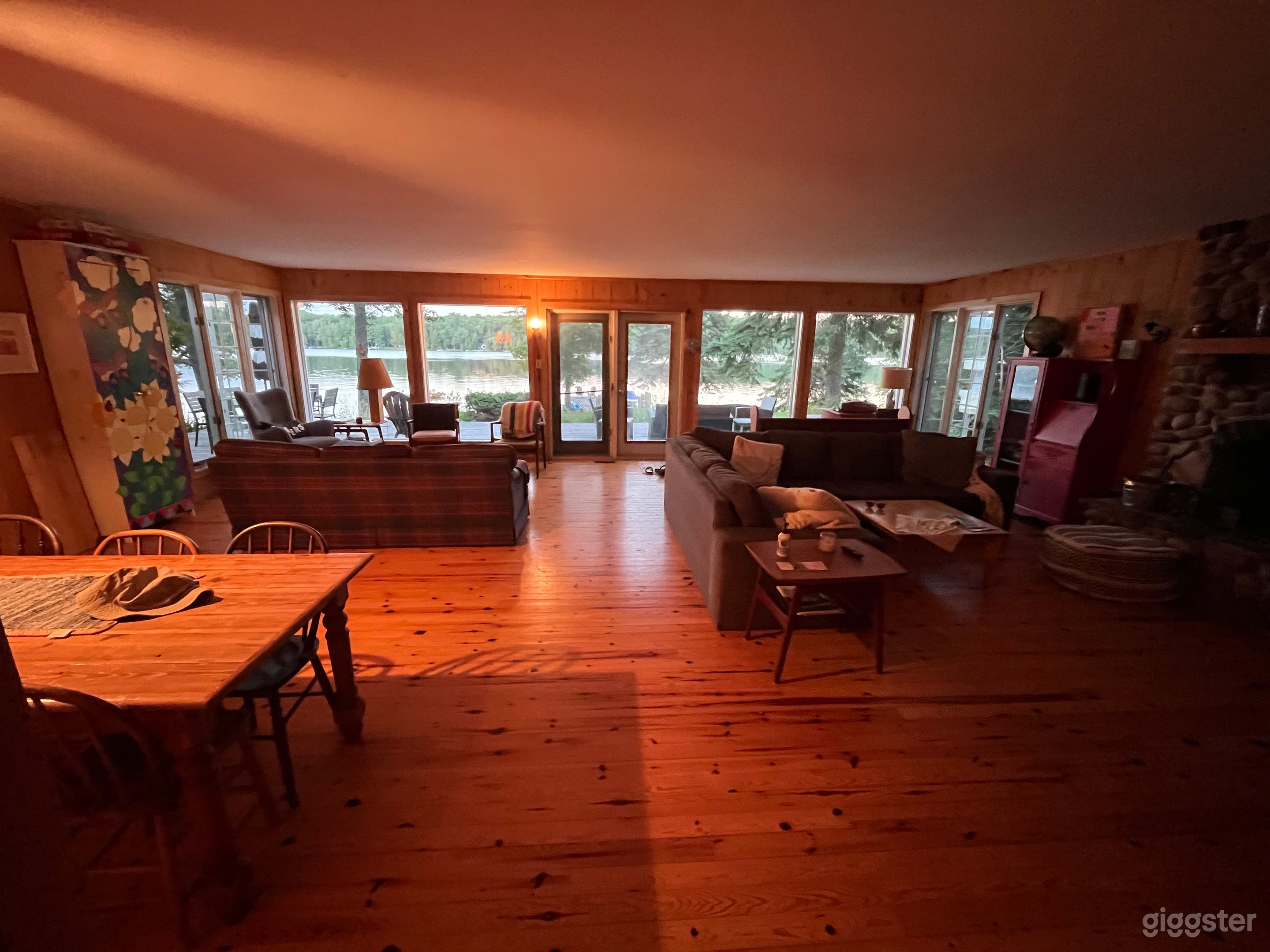 Large open concept wood cottage with floor to ceiling windows with beautiful view of lake.