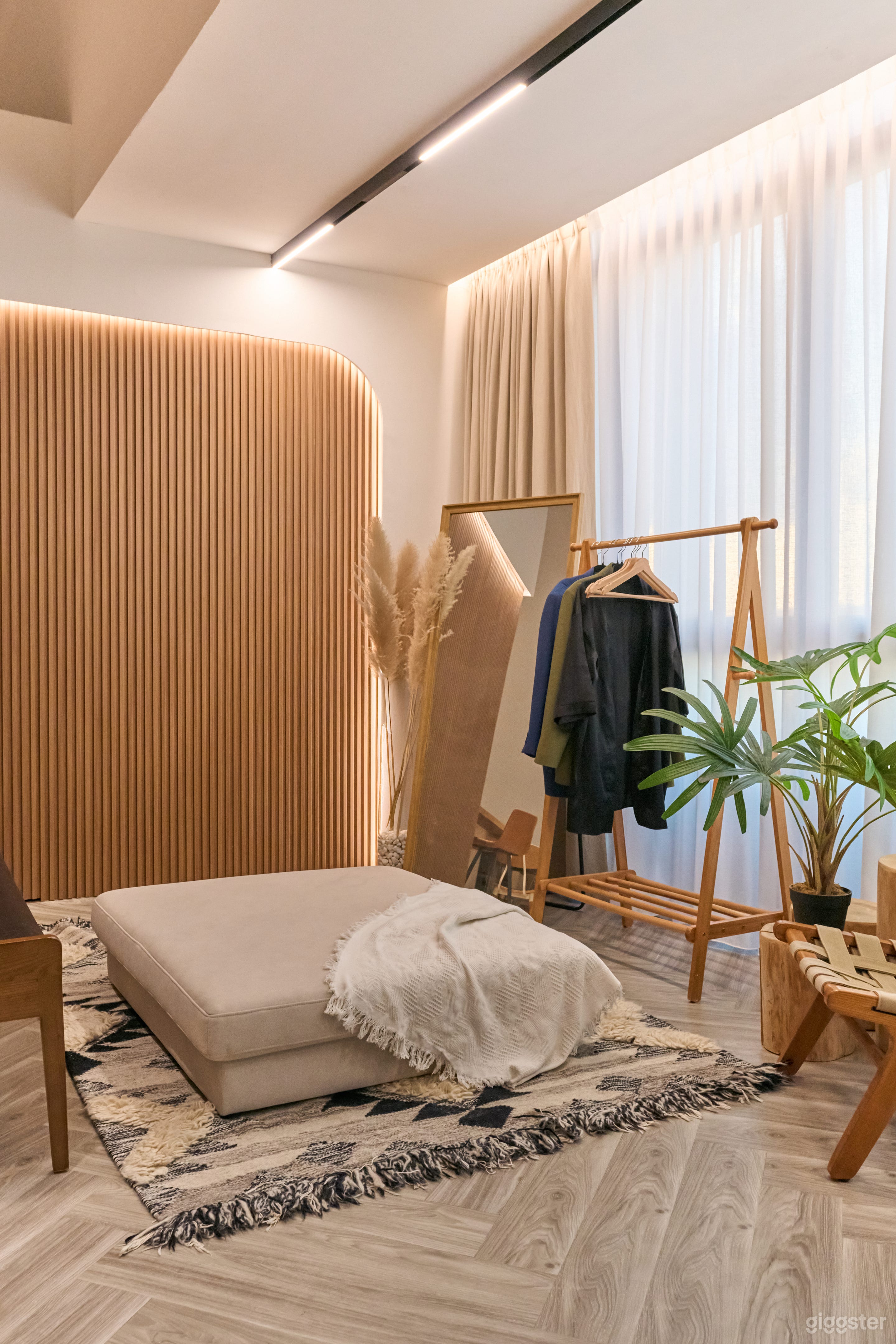 The studio features a stylish lounge and dressing area, complete with a full-body mirror set against elegant floor-to-ceiling windows. This inviting space is perfect for preparations, relaxation, or enjoying natural light while enhancing your creative expe