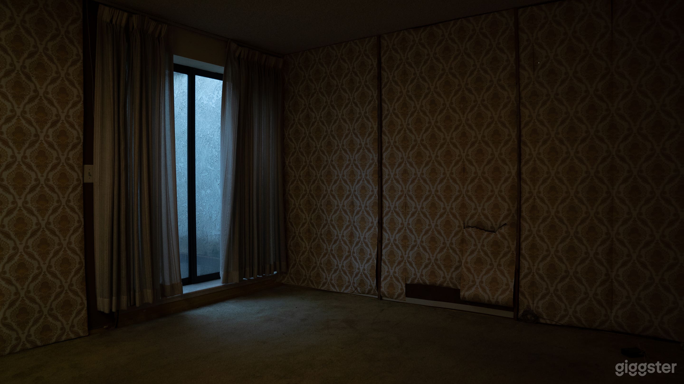 Empty Bedroom with vintage wallpaper and ugly wood paneling underneath.