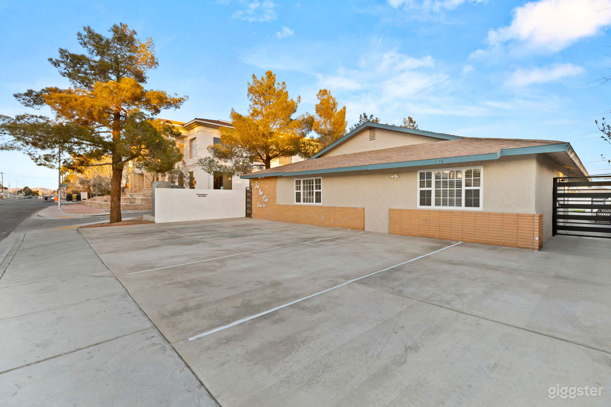 Property front showing large parking area and entry gate to right.
