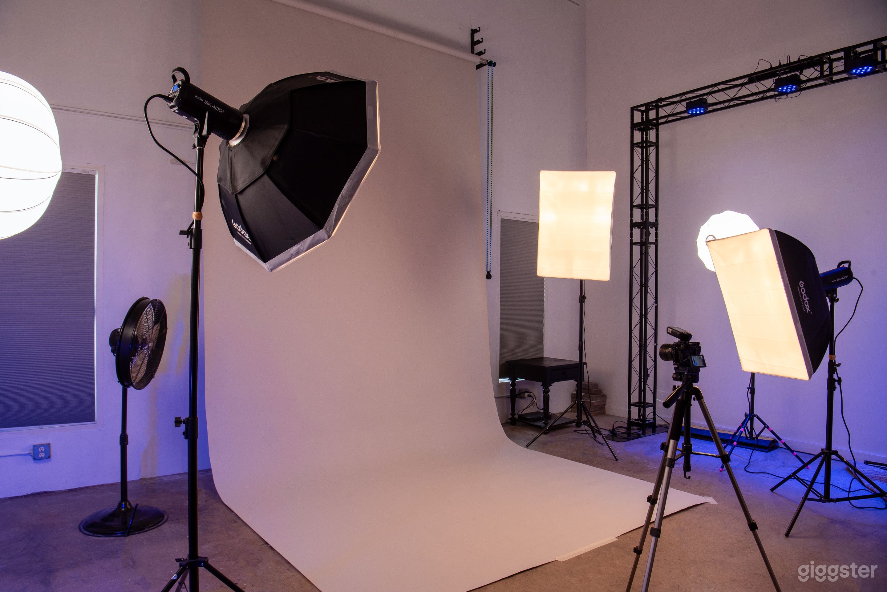 Photo studio corner, lighting stands, soft boxes and production station, seamless backdrop and trussing 