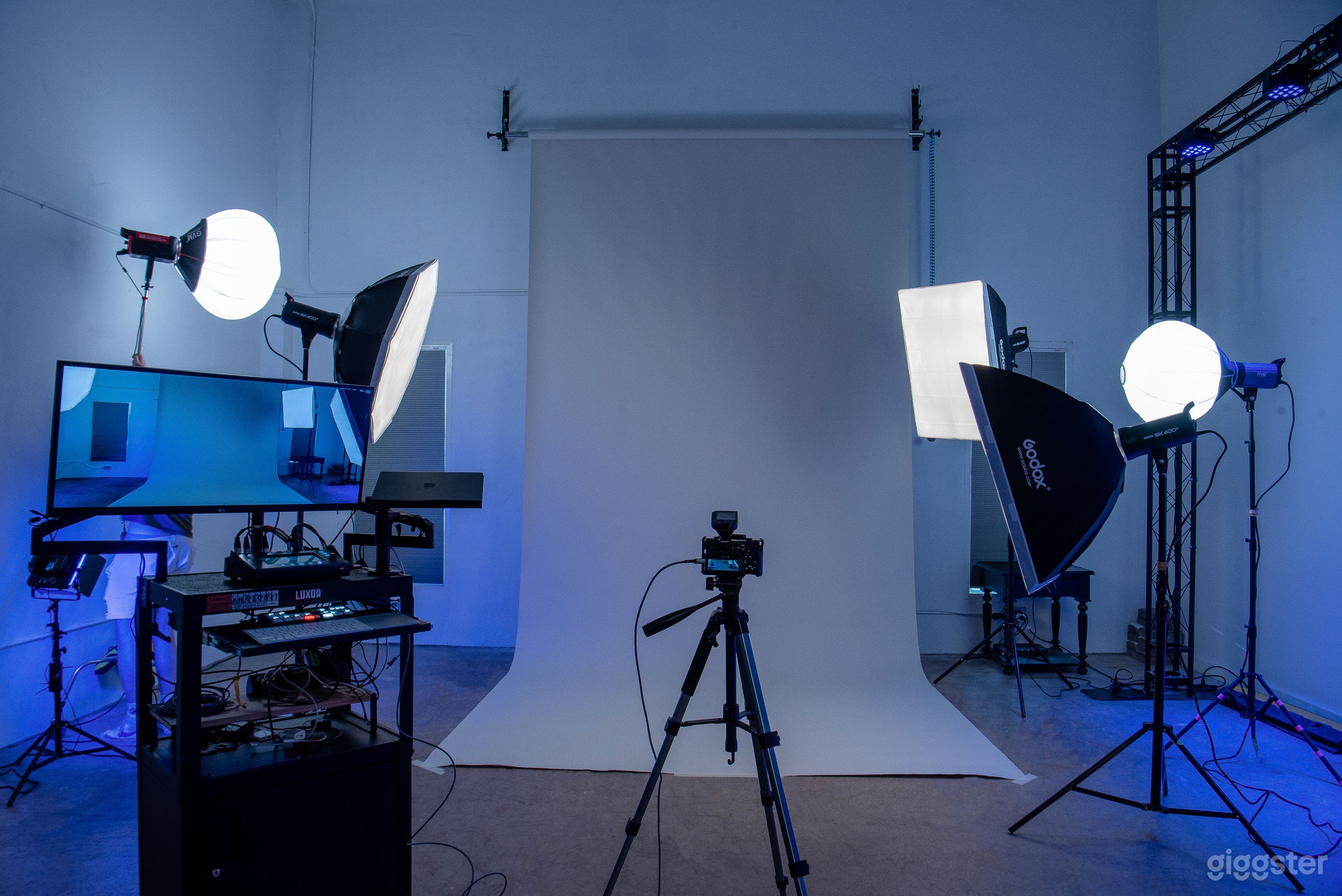 Photo studio corner, lighting stands, soft boxes and production station, seamless backdrop and trussing 