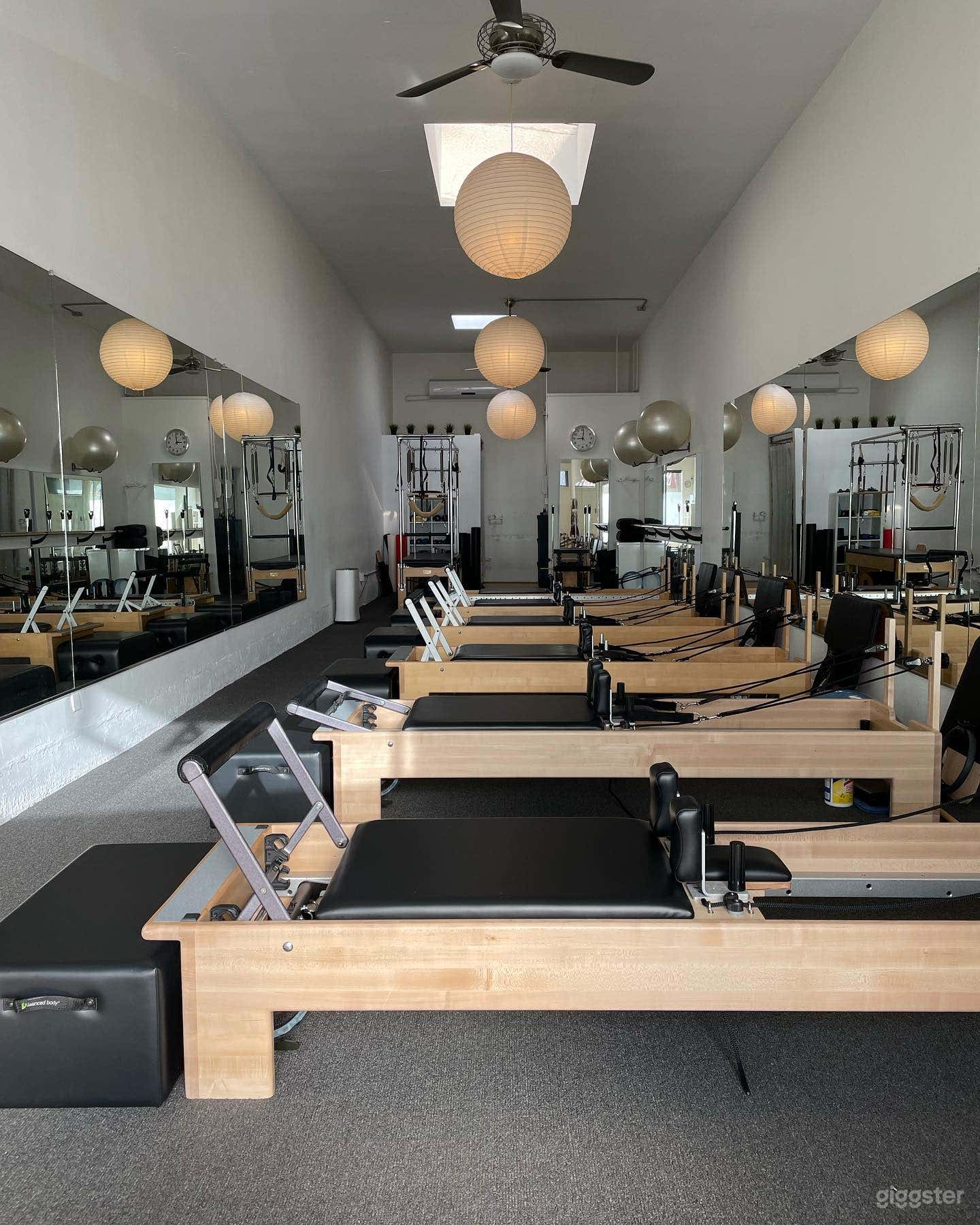 The bright interior of this Santa Monica Pilates studio features natural light from skylights and large windows. Equipped with Balanced Body Reformers, the clean, modern design creates a serene atmosphere ideal for photo and video shoots.