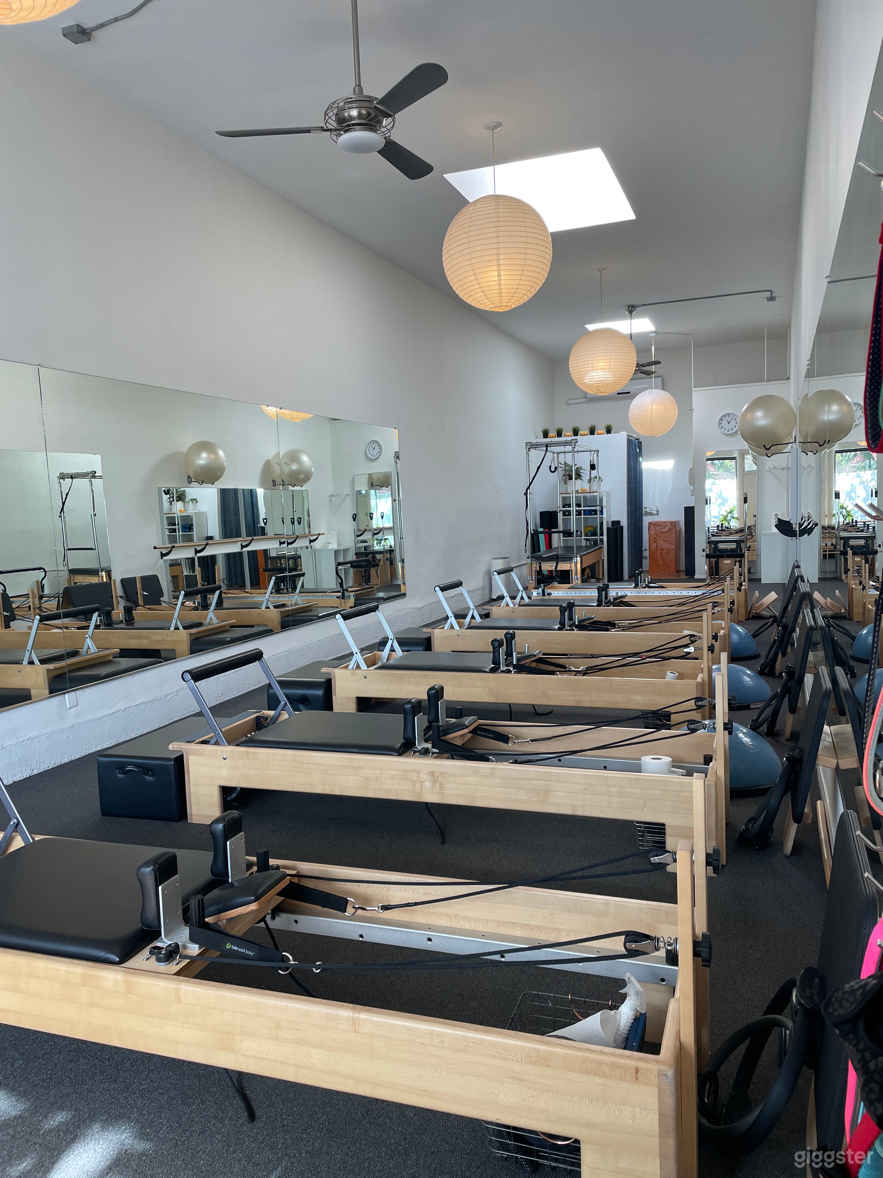 The bright interior of this Santa Monica Pilates studio features natural light from skylights and large windows. Equipped with Balanced Body Reformers, the clean, modern design creates a serene atmosphere ideal for photo and video shoots.