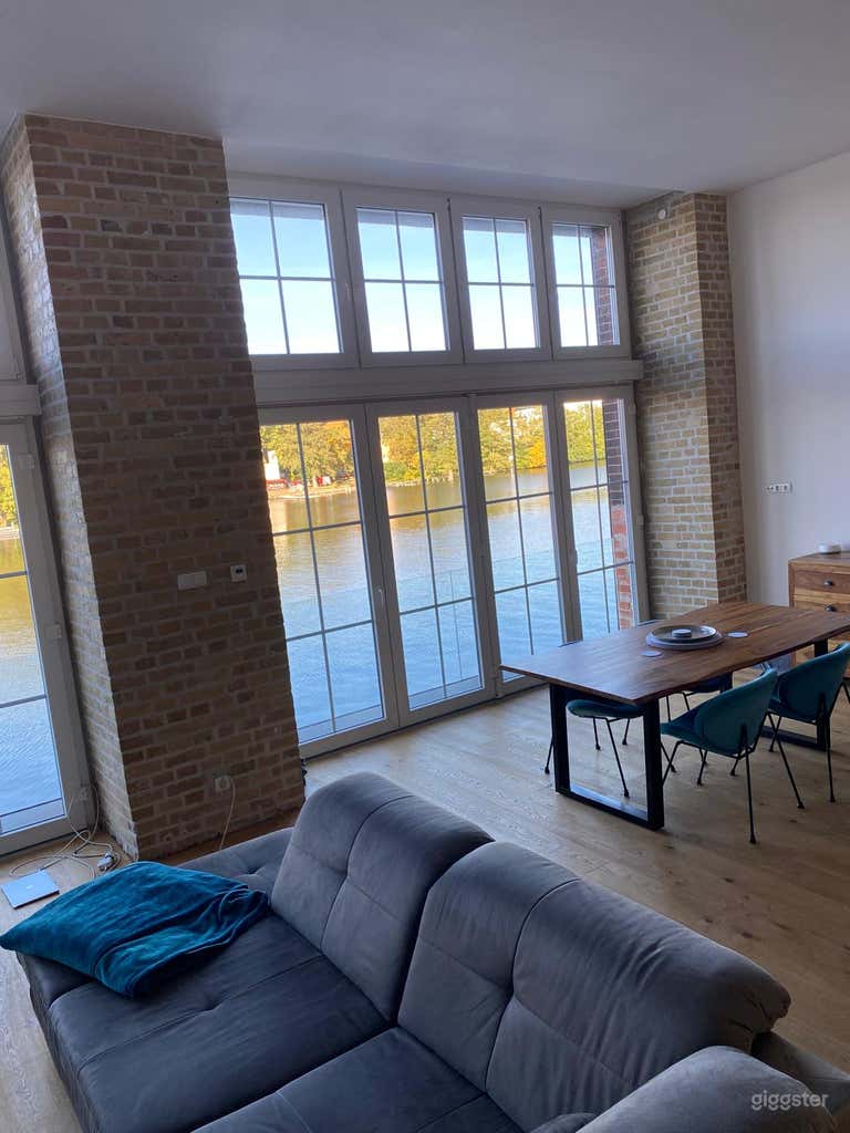  Helles Loft am Wasser mit bodentiefen Fenstern und Holzböden – flexible Einrichtung für Essensszenen, Workshops oder kreative Treffen. 