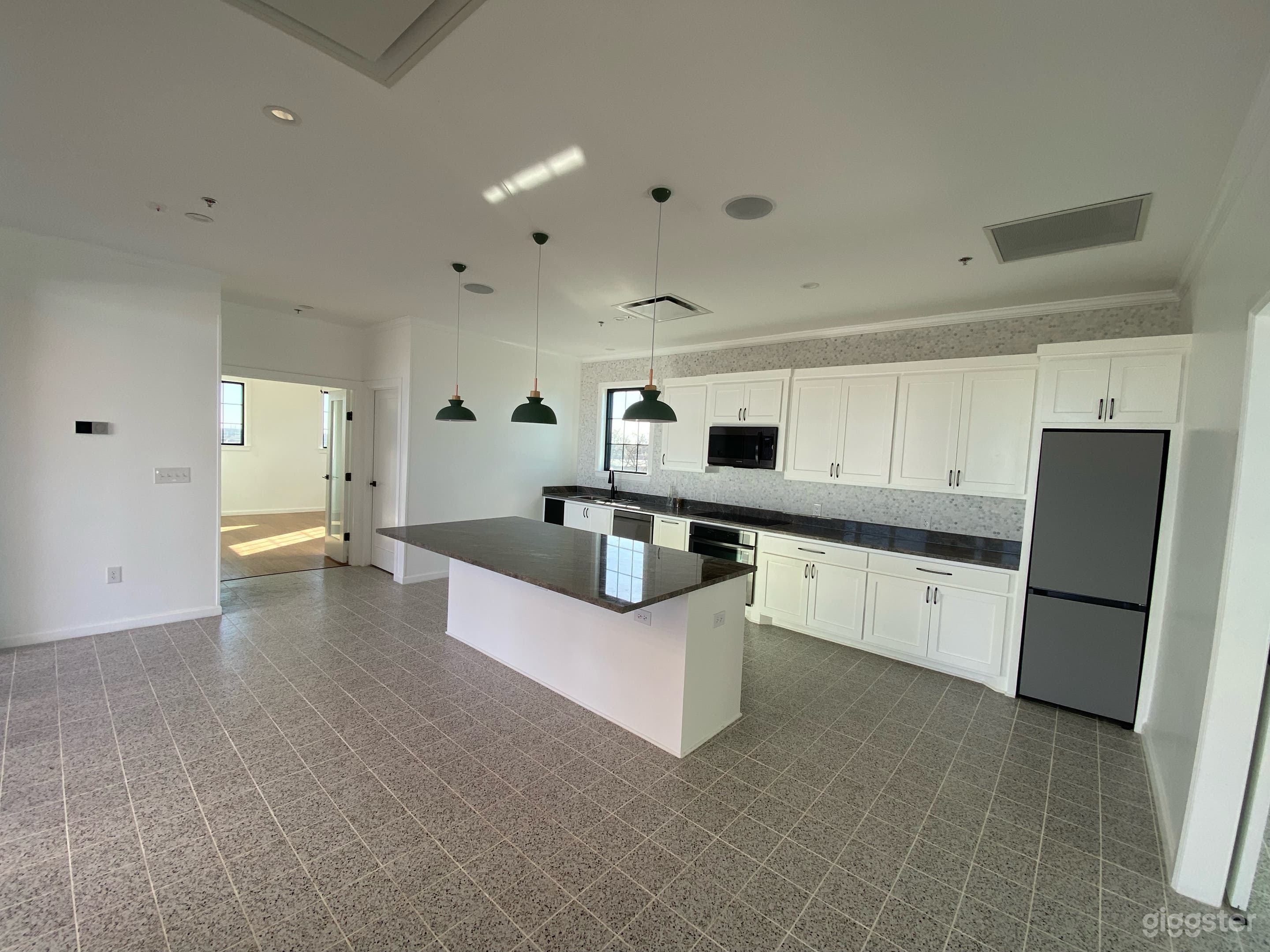 Open Kitchen area. Island in the center, there is a stove, oven, sink, and refrigerator. 