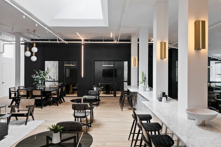  The space has a mix of high level marble bar space, large wooden table, and glass and steel round tables. 