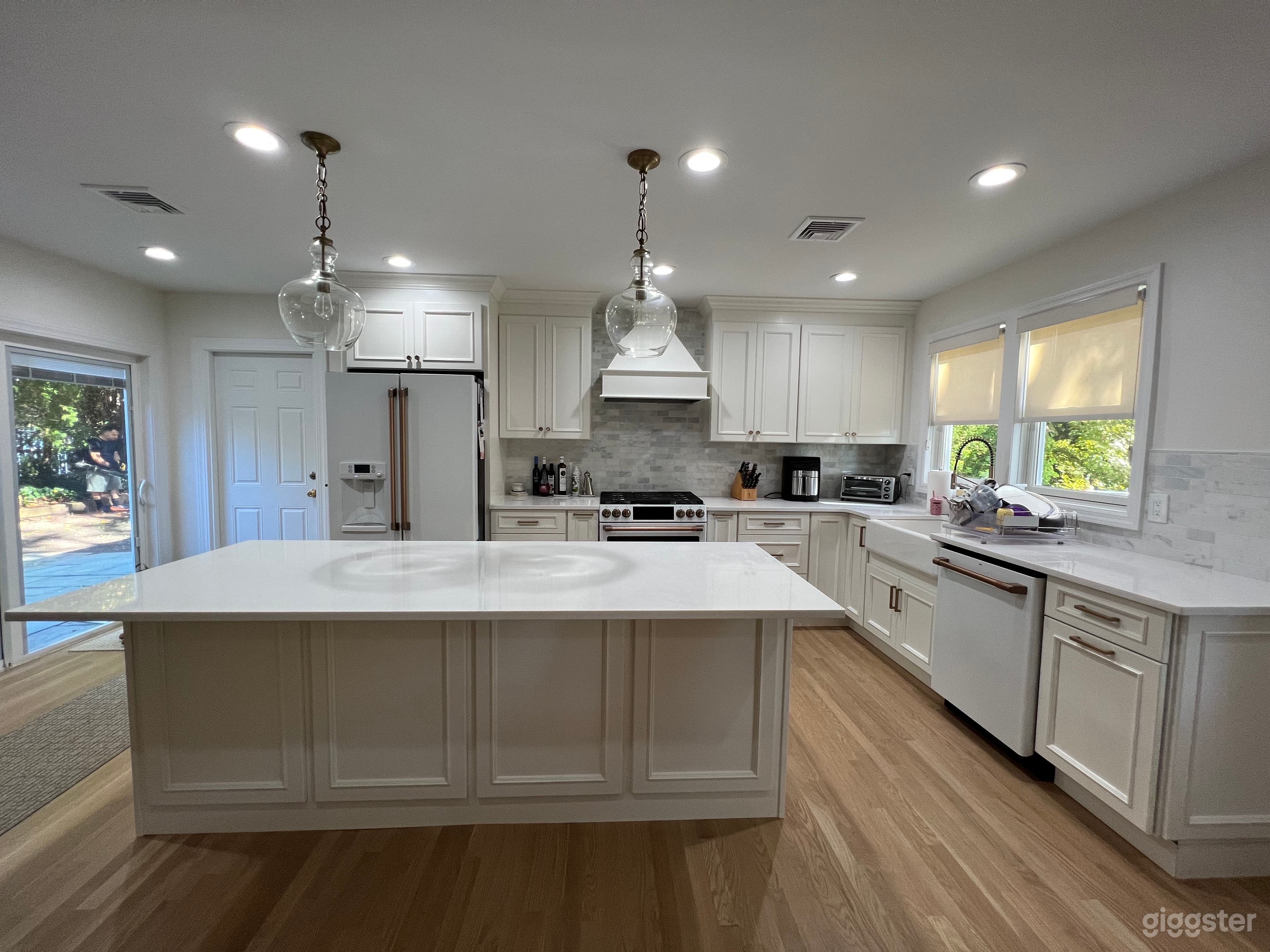 Brand new white kitchen with satin brass knobs and pulls, as well as Cafe line appliances with rose gold finishes.
