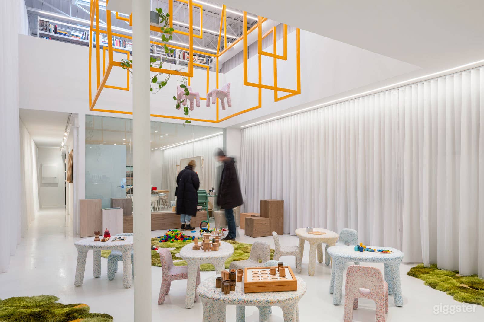 Double height atrium space.  Curtains line white CMU walls and a concealed coffee station.  Furniture set up was temporary for a kids event.  