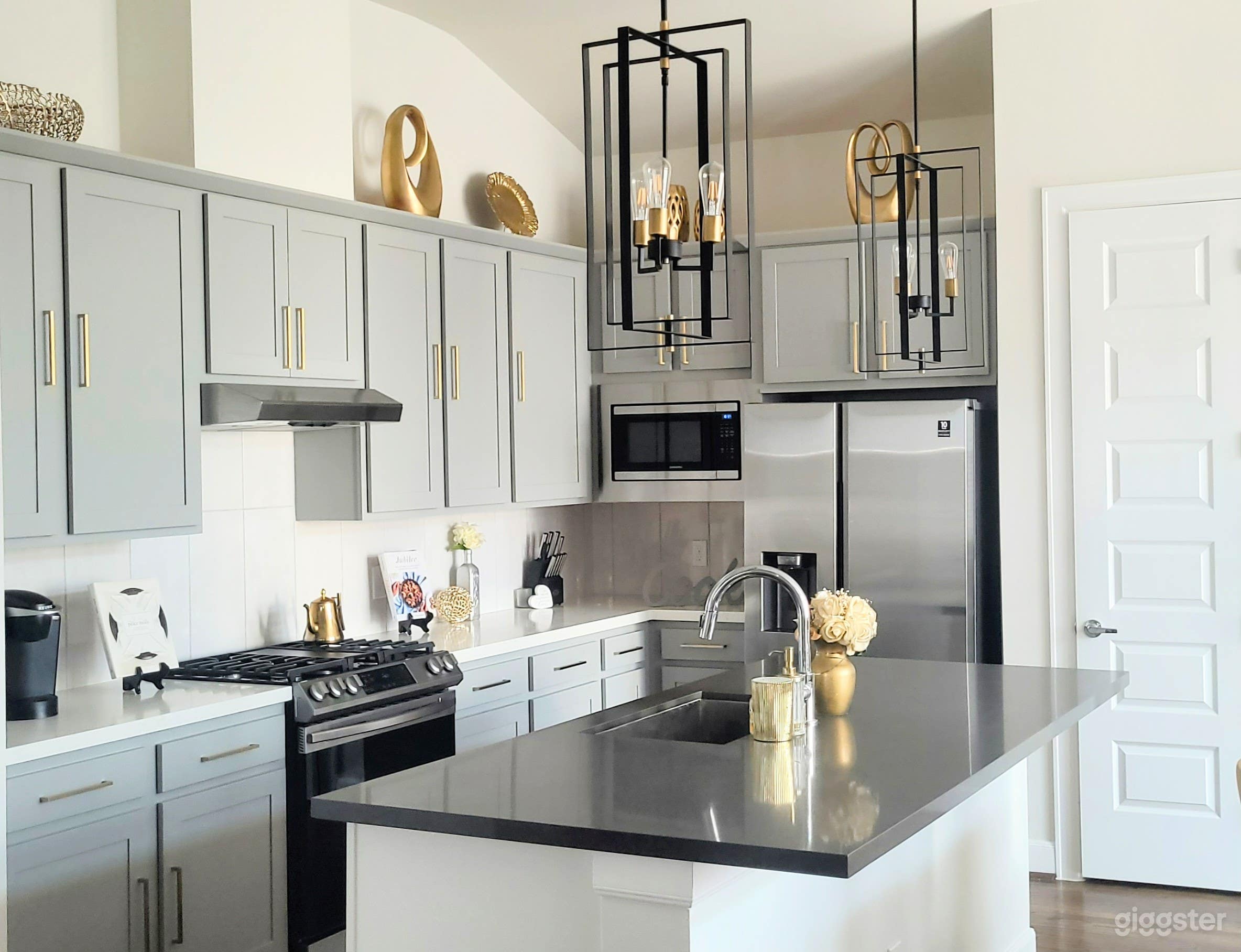 Modern neutral kitchen with sleek gray cabinets, elegant gold hardware and stainless steel appliances