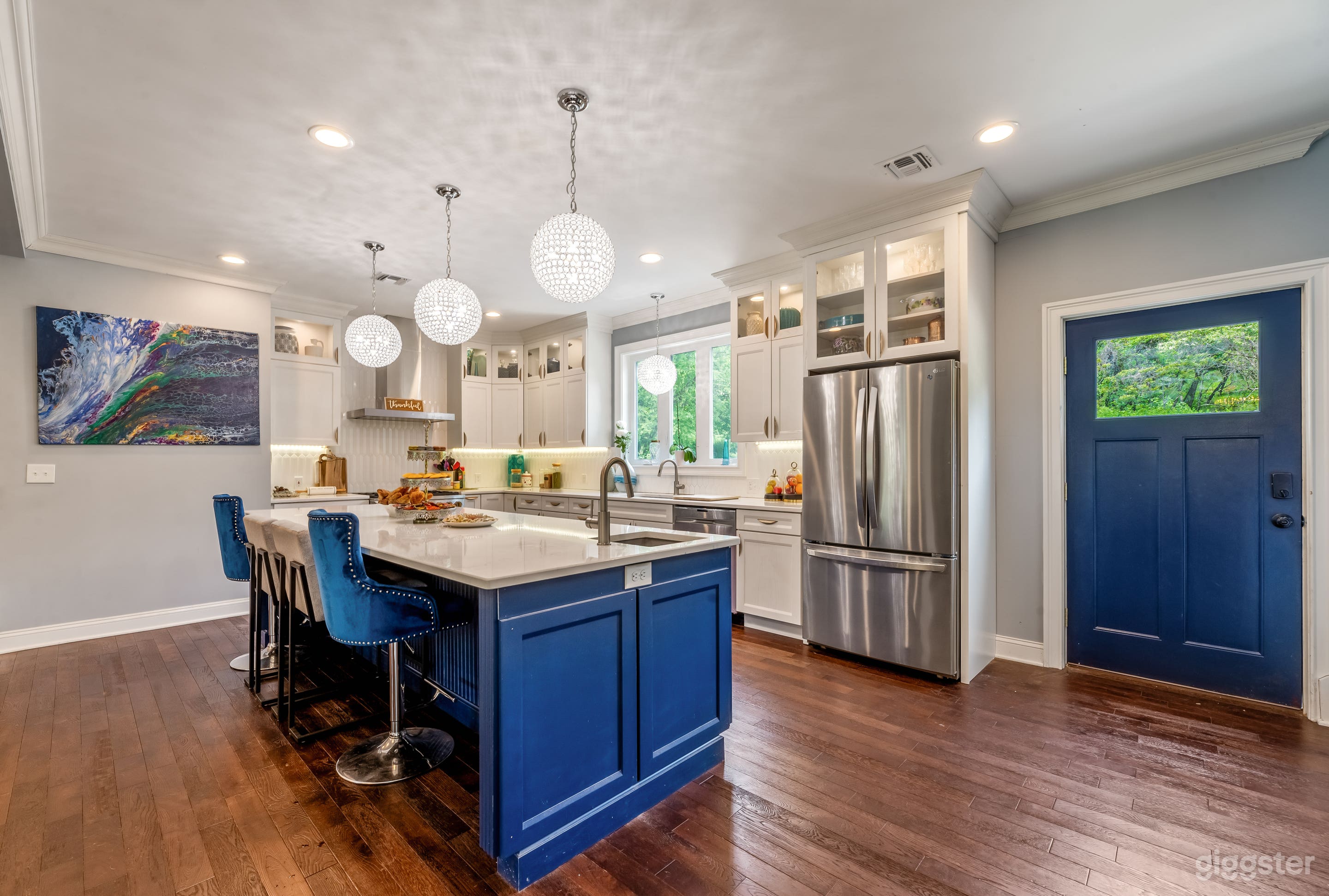 large open white kitchen with blue island and stunning lighting