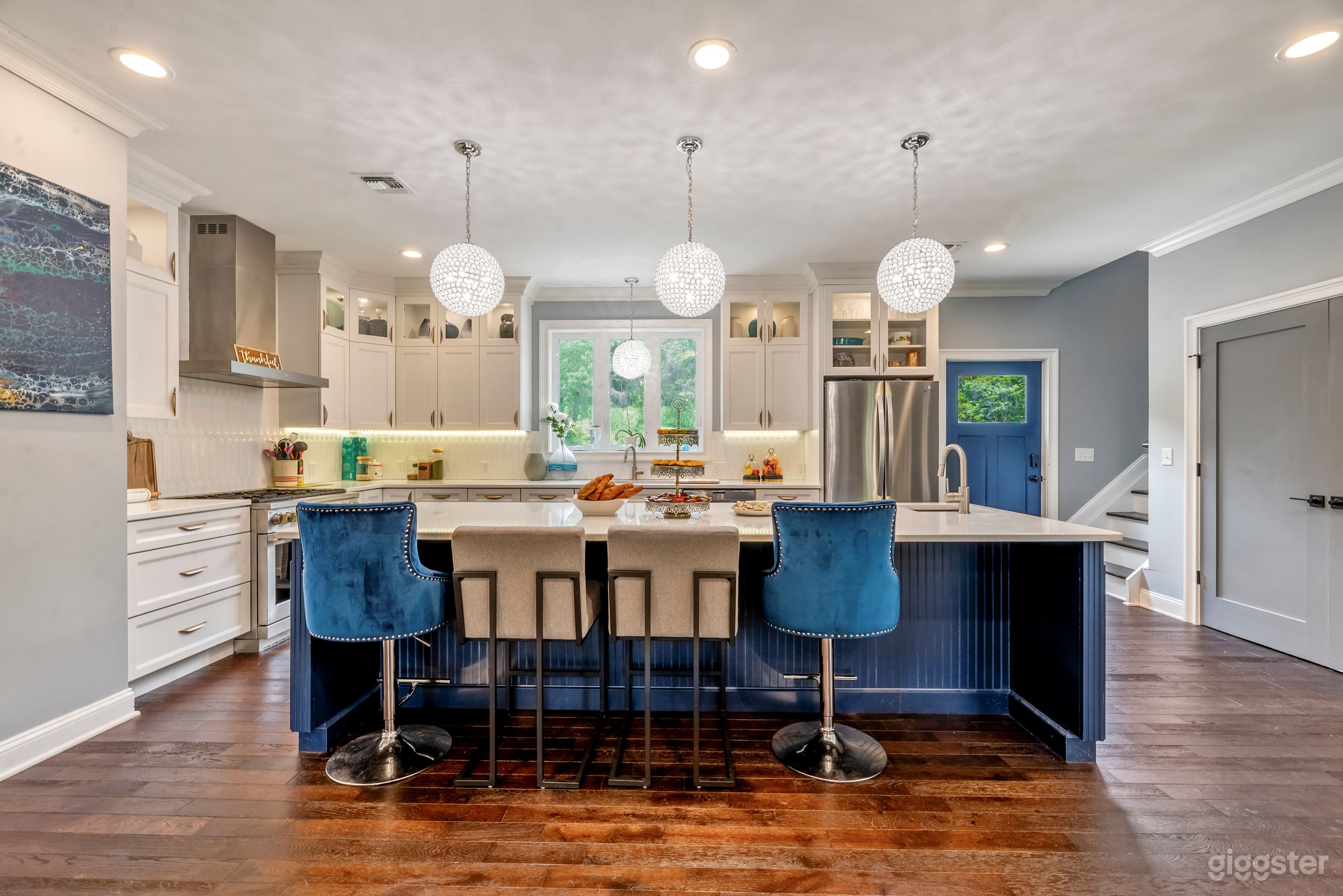 large open kitchen with blue island and stacked white cabinets