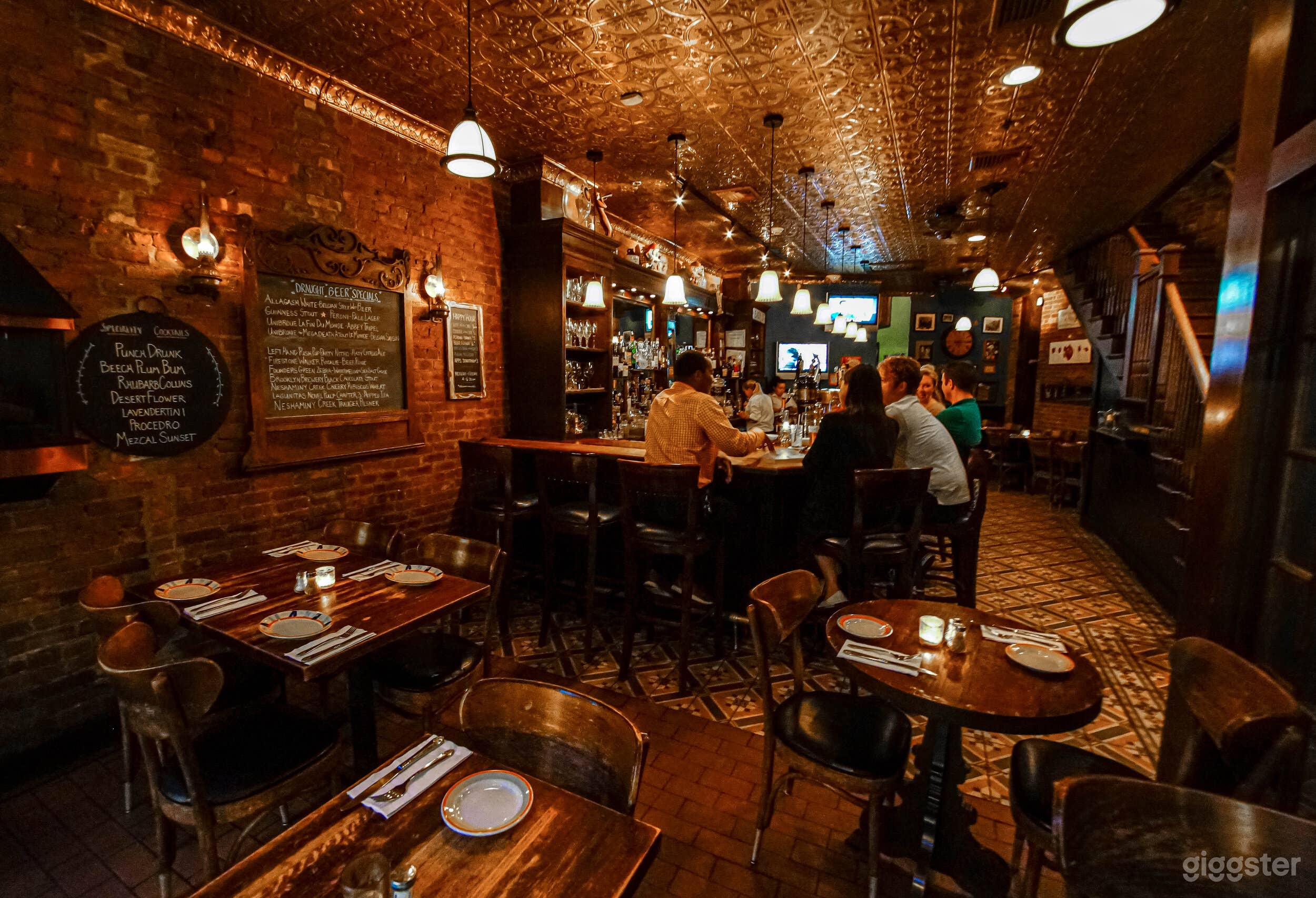 View of the bar and pub dining area. The ceiling is copper, and many of the walls throughout are exposed brick.